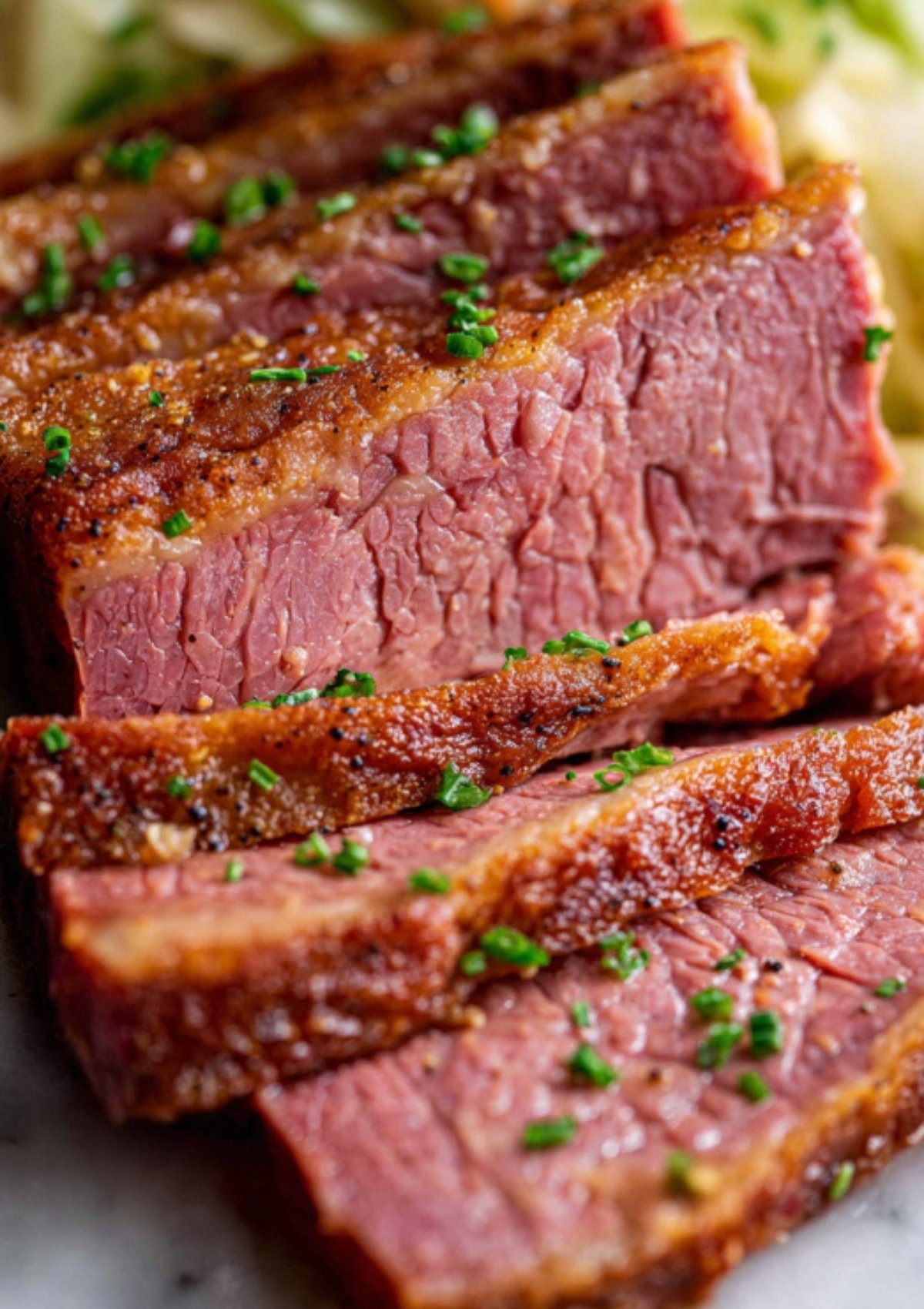 Thick, tender slices of corned beef with a crispy seasoned crust, sprinkled with chives, showing the juicy and flavorful texture of this easy comfort food recipe.