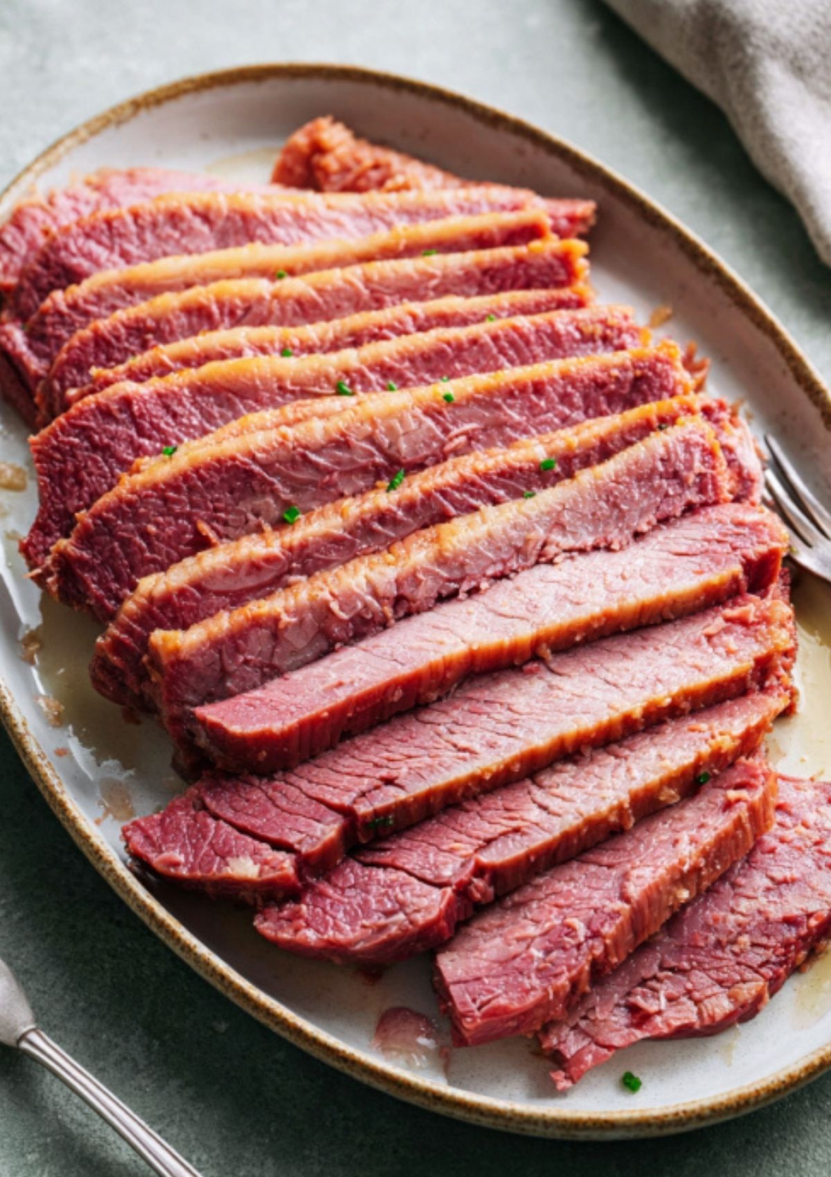 Sliced homemade corned beef brisket arranged on a serving platter, showing juicy, tender texture