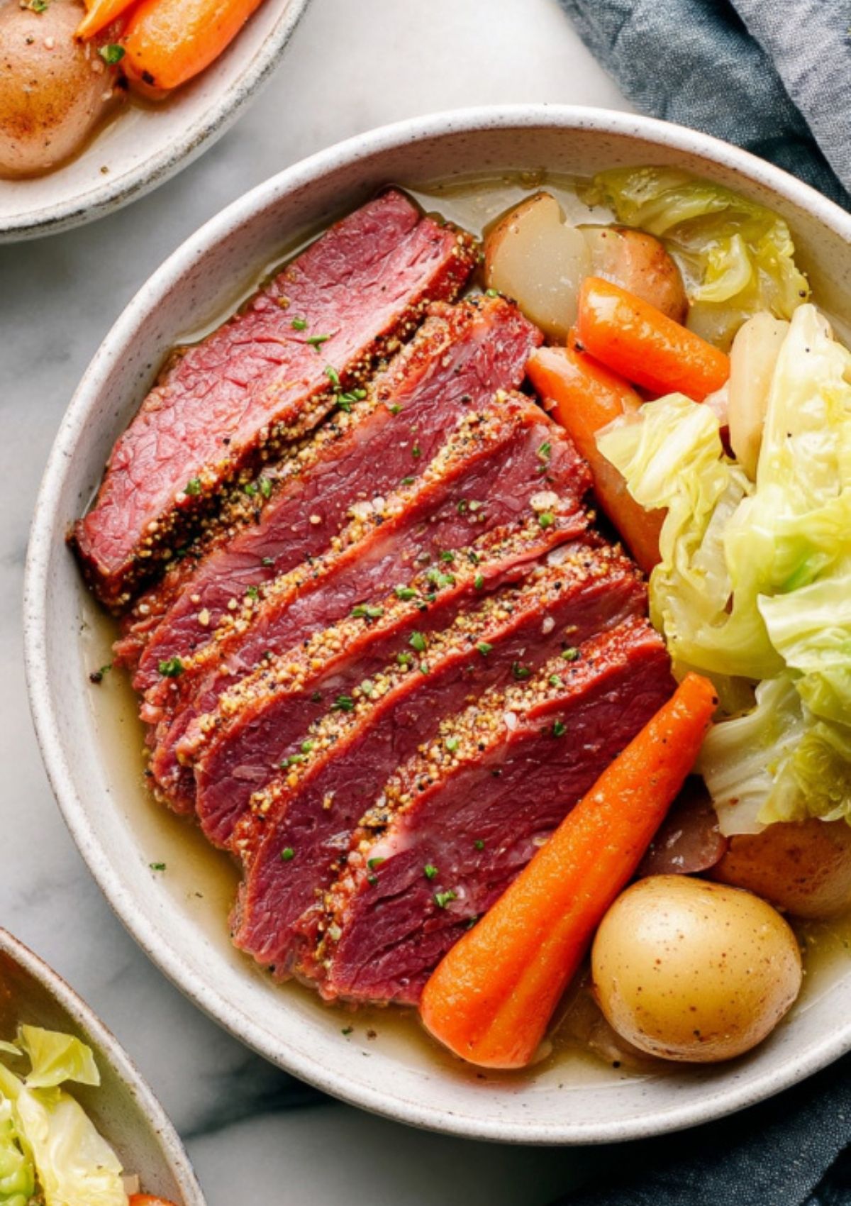 Sliced corned beef on a plate with cooked cabbage, carrots, and potatoes, a classic St. Patrick’s Day meal.