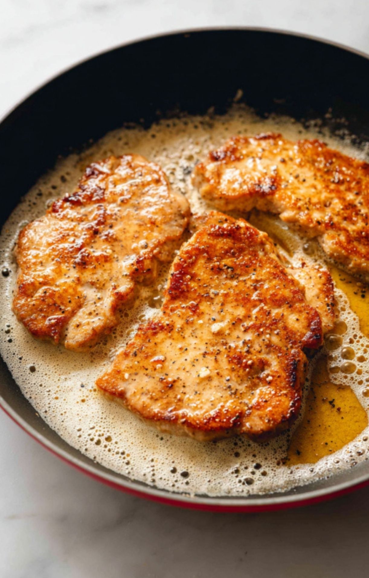 Sliced mushrooms and capers cooking in a pan with savory white wine sauce. Simple, rich topping for authentic veal scallopini dinners.