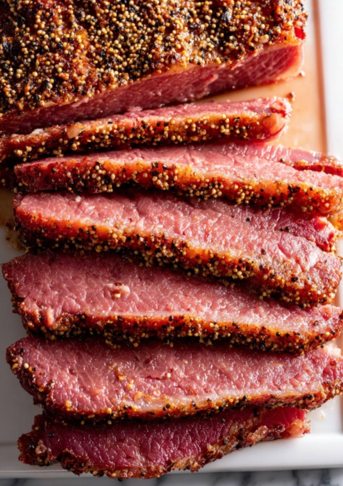 Sliced flat cut corned beef brisket with a savory seasoning crust, arranged for serving. This recipe makes juicy slices, perfect for sandwiches or classic Irish meals.