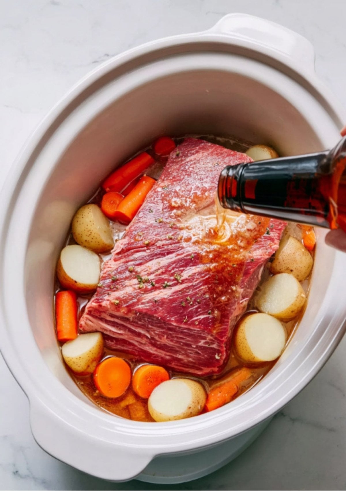 Pouring beer over corned beef, carrots, and potatoes in the Instant Pot. This step brings bold flavor to this fast, one-pot St. Patrick’s Day dinner.