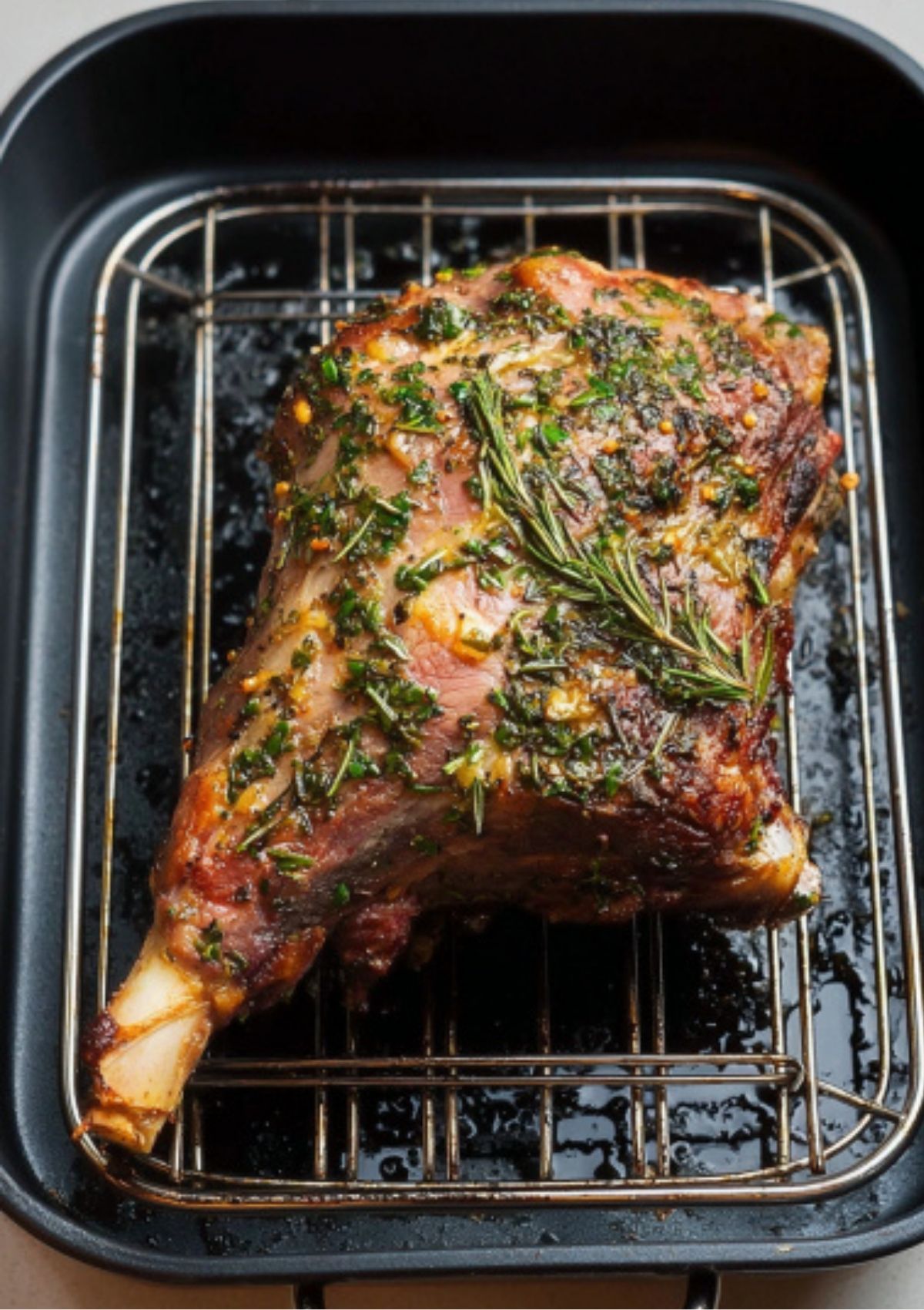 Roast leg of lamb coated with garlic and herbs in a roasting pan