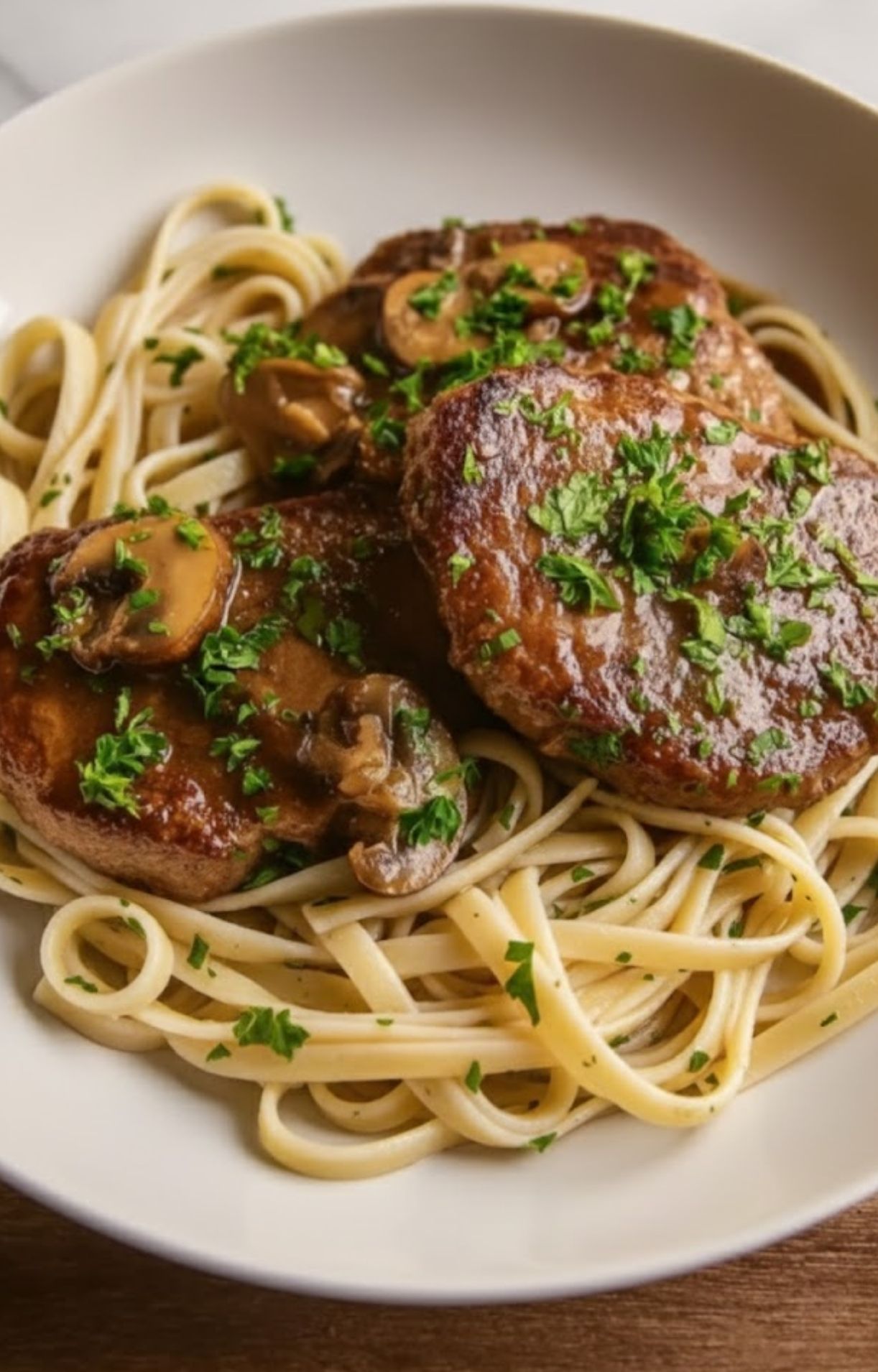 Tender marsala veal scallopini with mushrooms served over pasta and topped with parsley, a simple Italian meal for weeknights or holidays