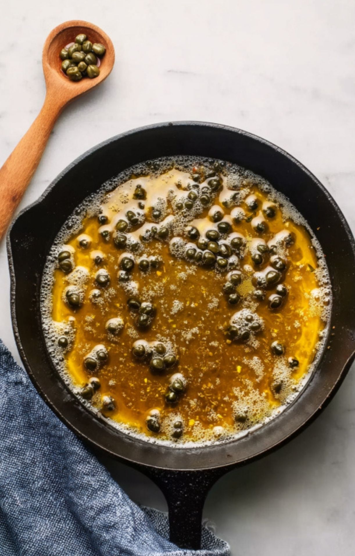 Skillet with lemon caper sauce for classic veal scallopini recipe, perfect for spring dinners and quick weeknight meals.