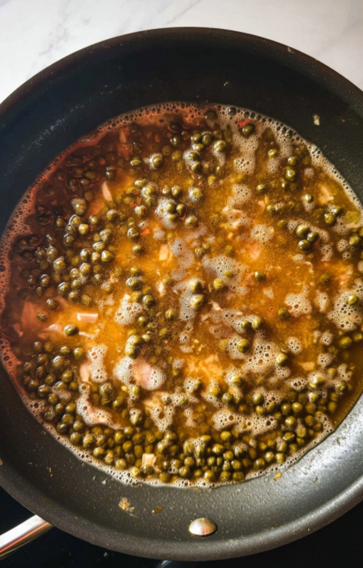 Finished veal piccata in a cast iron skillet, topped with lemon slices, capers, and fresh parsley. The perfect Italian dinner for weeknights or special occasions.