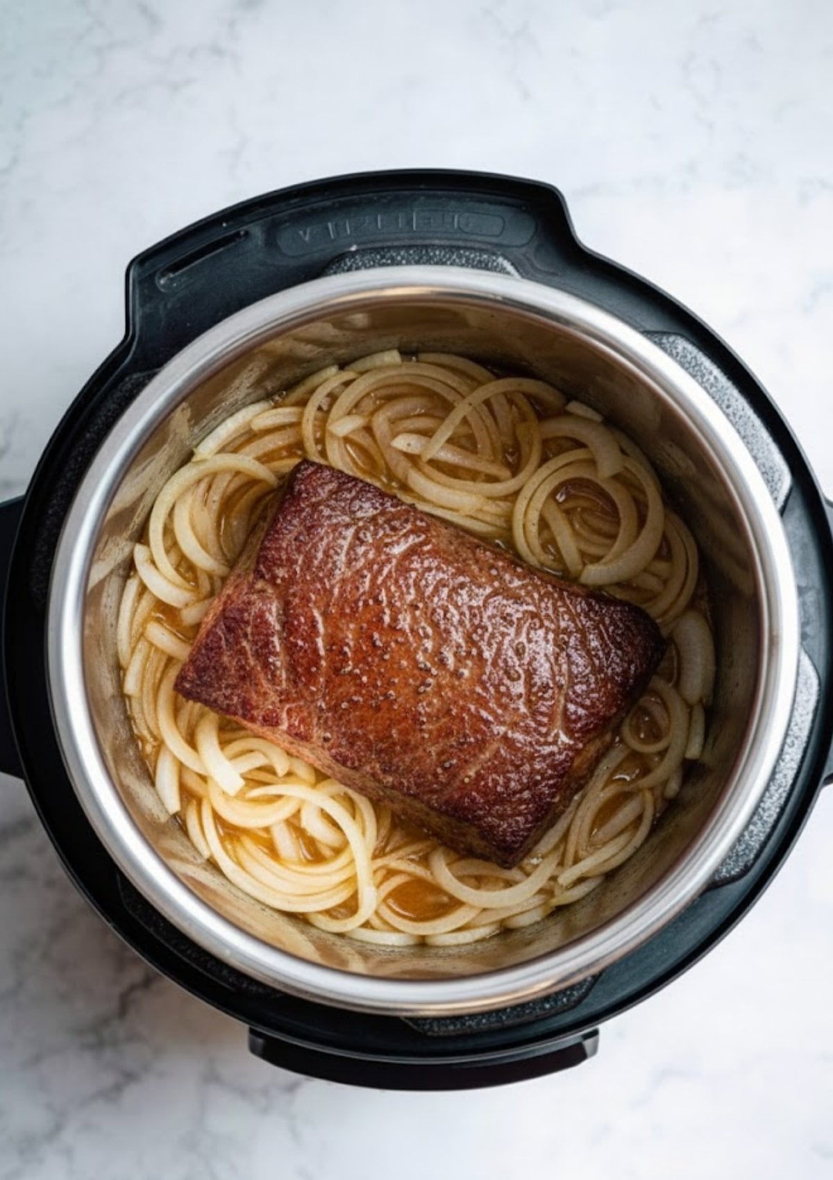 Brisket being sautéed with sliced onions in an Instant Pot. Step for locking in flavor before pressure cooking classic corned beef, perfect for beginners.