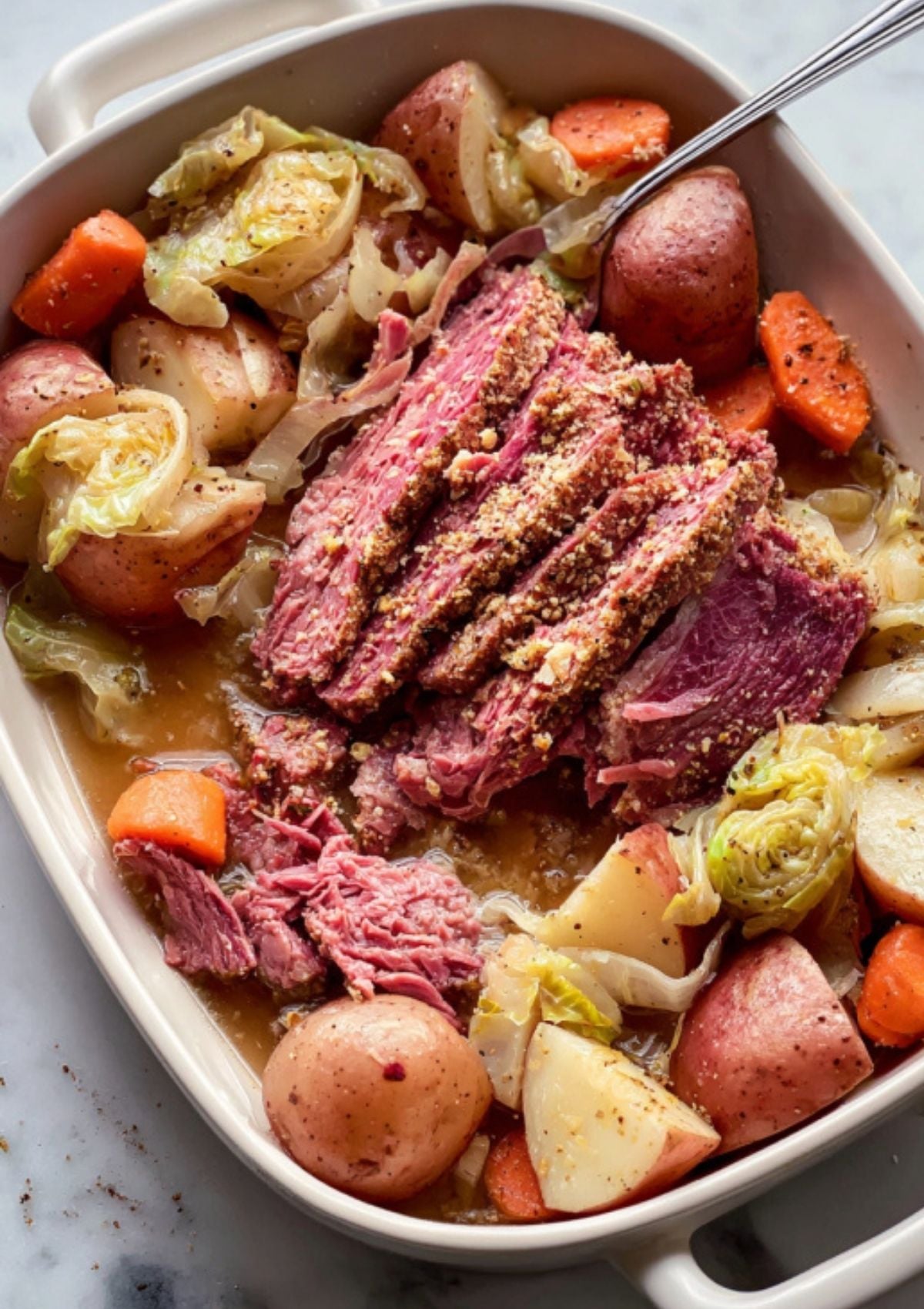 Sliced Dutch oven corned beef brisket served with red potatoes, carrots, and cabbage in a savory broth. Classic Irish comfort food, perfect for St. Patrick’s Day or family dinner.