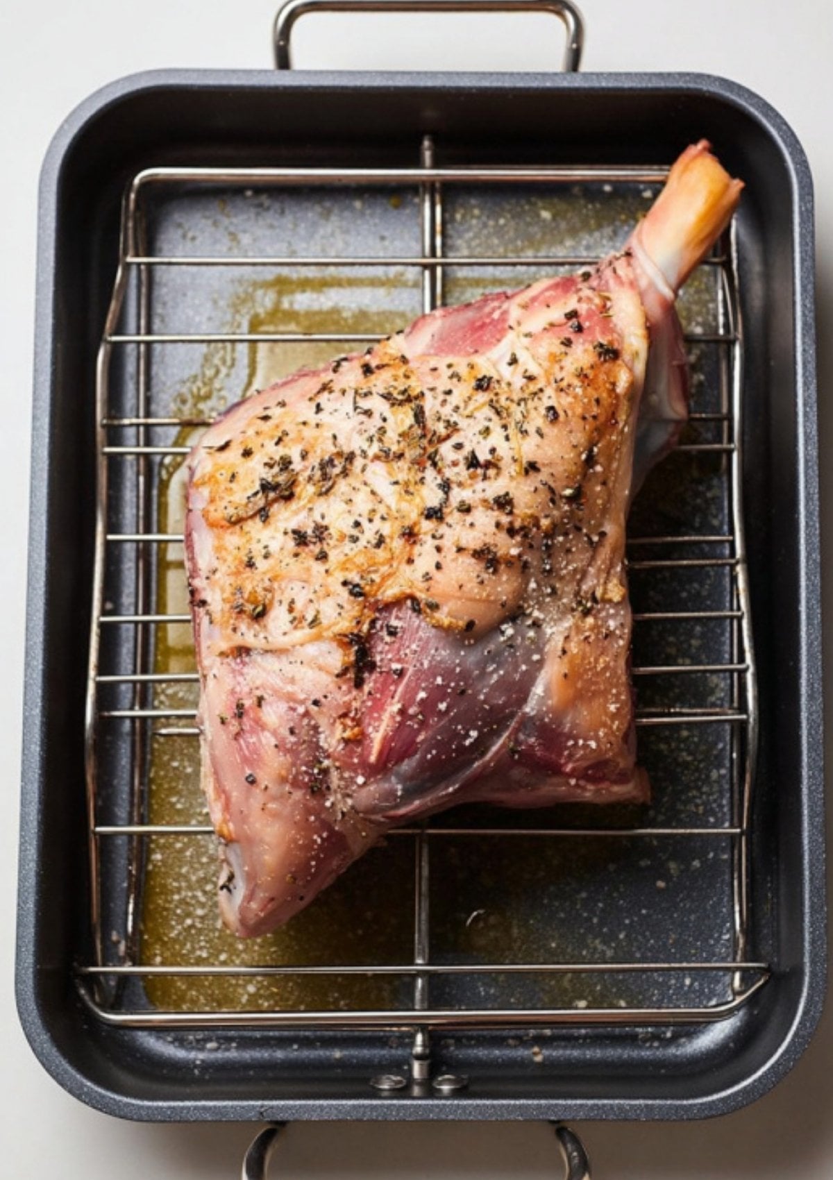 Raw bone-in leg of lamb seasoned and placed on a roasting rack