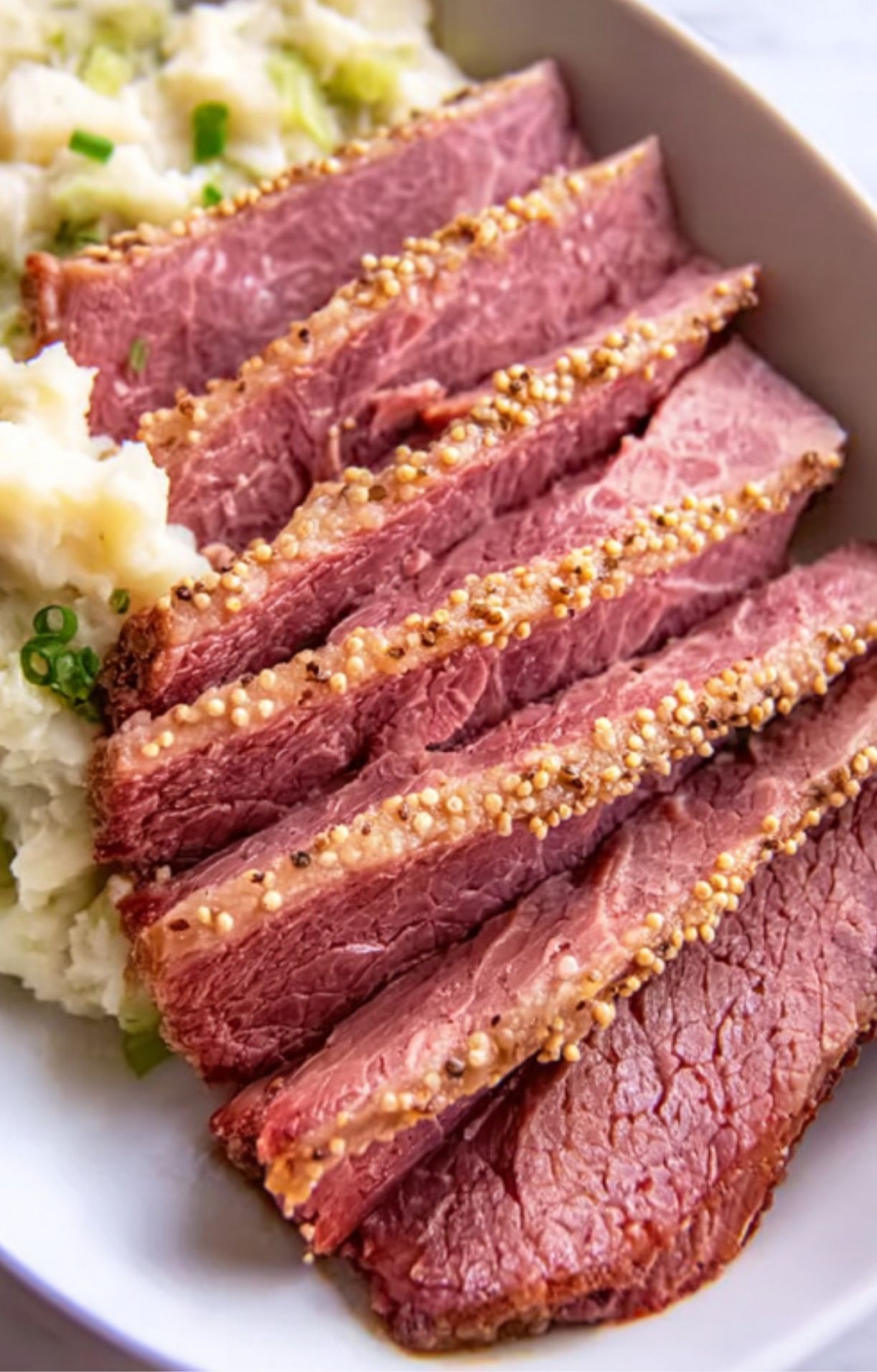 Slices of Guinness braised corned beef served with mashed potatoes and mustard seeds, perfect Irish dinner