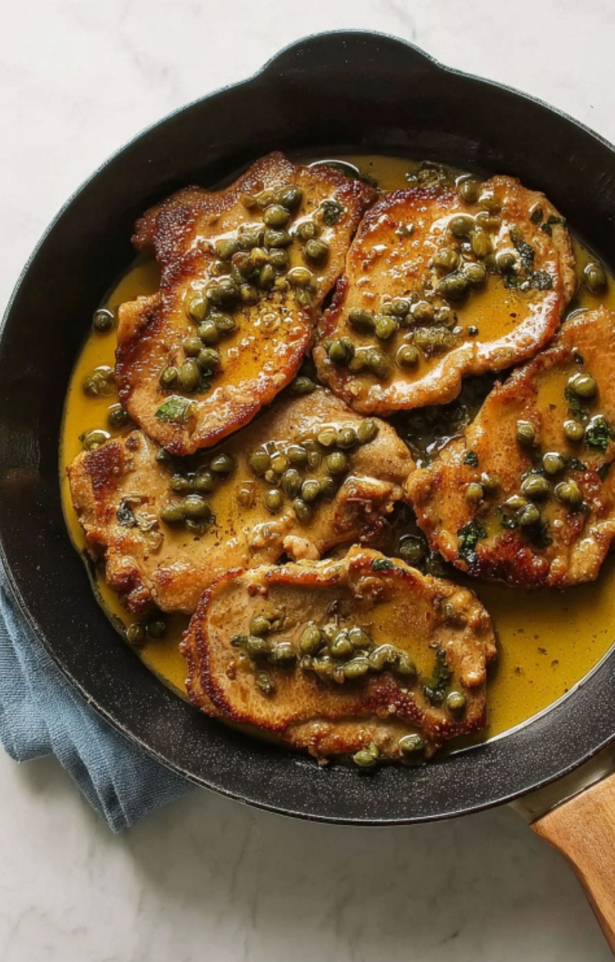 Finished veal scallopini simmering in lemon caper pan sauce, easy homemade Italian dinner.