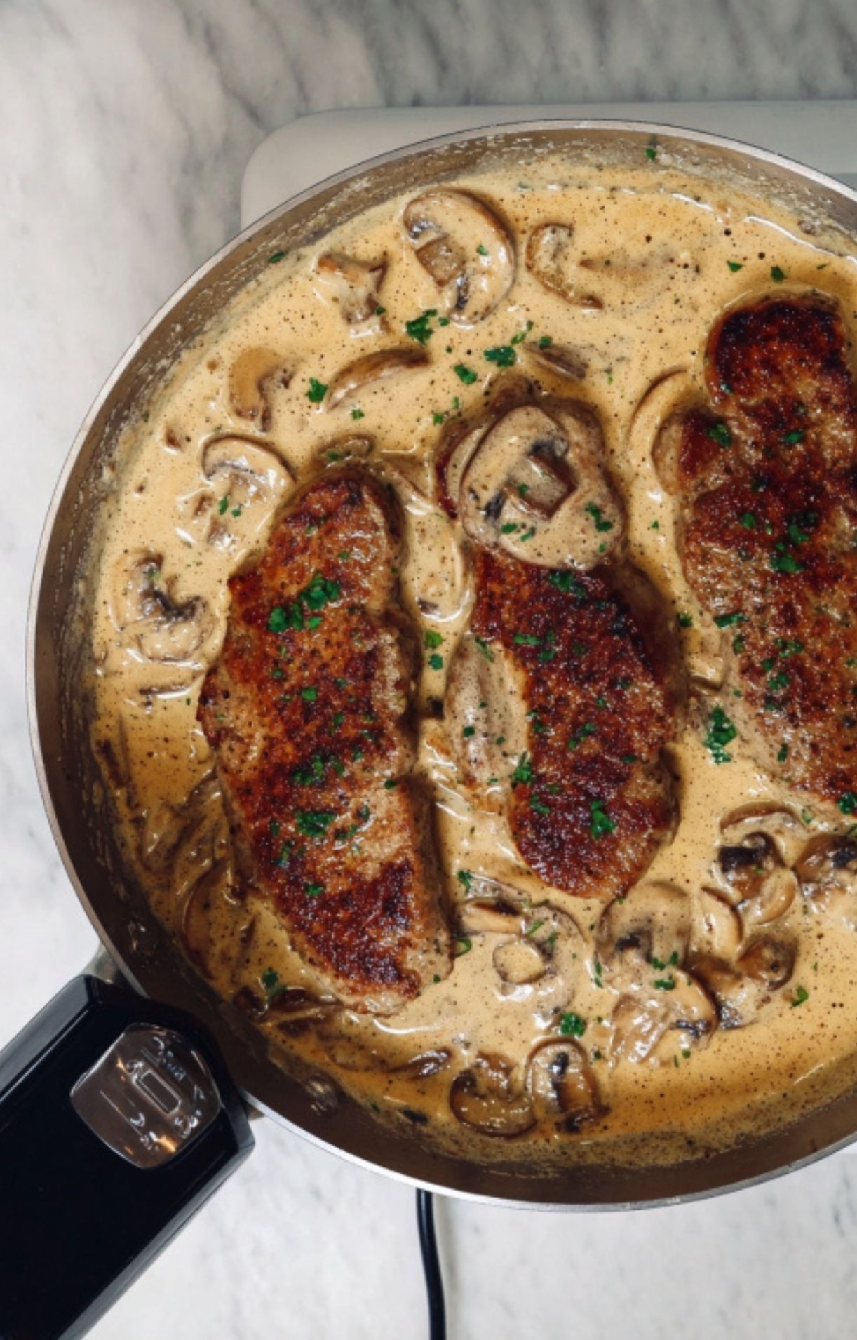 Golden seared veal cutlets simmering in a creamy mushroom sauce with fresh herbs, perfect for a cozy Italian dinner or special occasion.