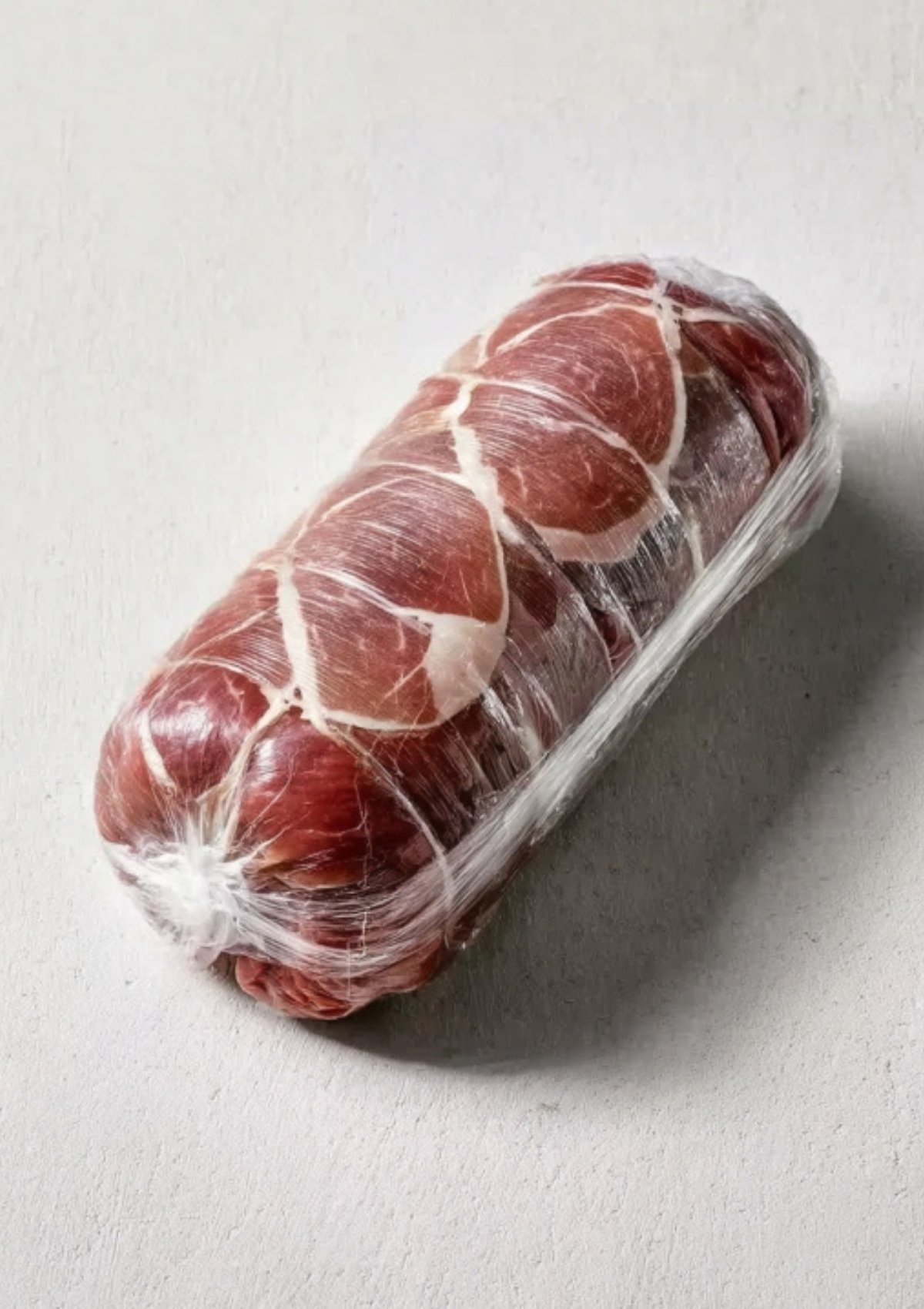 Beef tenderloin wrapped in prosciutto and plastic wrap to seal in flavor and moisture for beef Wellington puff pastry, a top holiday recipe.