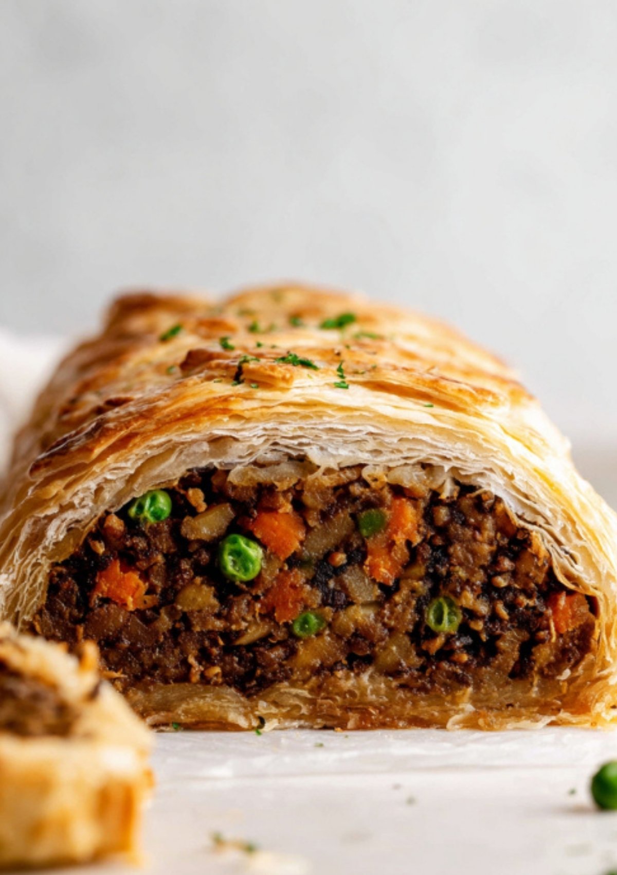 Sliced vegan Wellington revealing a rich, vegetable-packed filling wrapped in layers of golden, flaky pastry. Served for a cozy winter dinner or festive holiday meal.