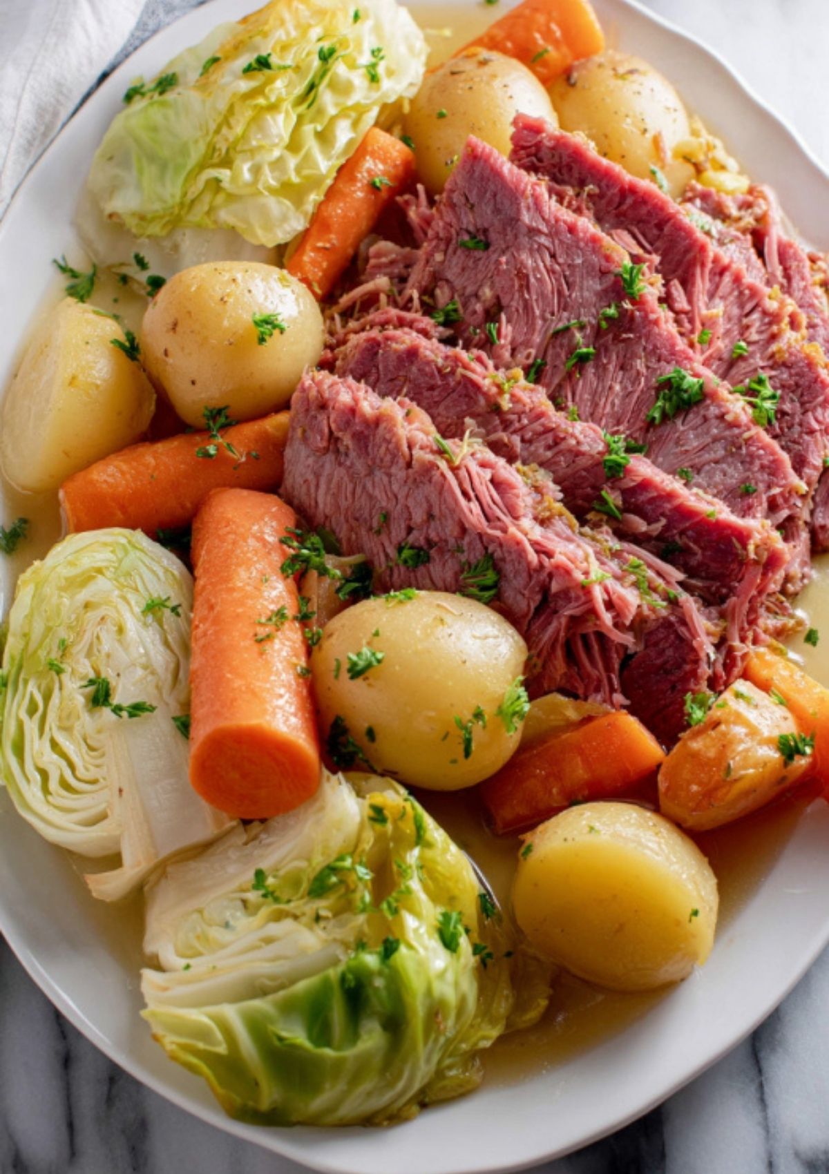 Colorful plate of traditional corned beef, green cabbage, carrots, and potatoes, all cooked together for an authentic Irish comfort food meal.
