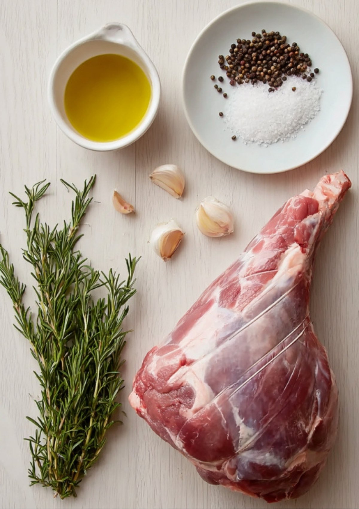 Raw leg of lamb with rosemary, garlic, olive oil, salt, and pepper