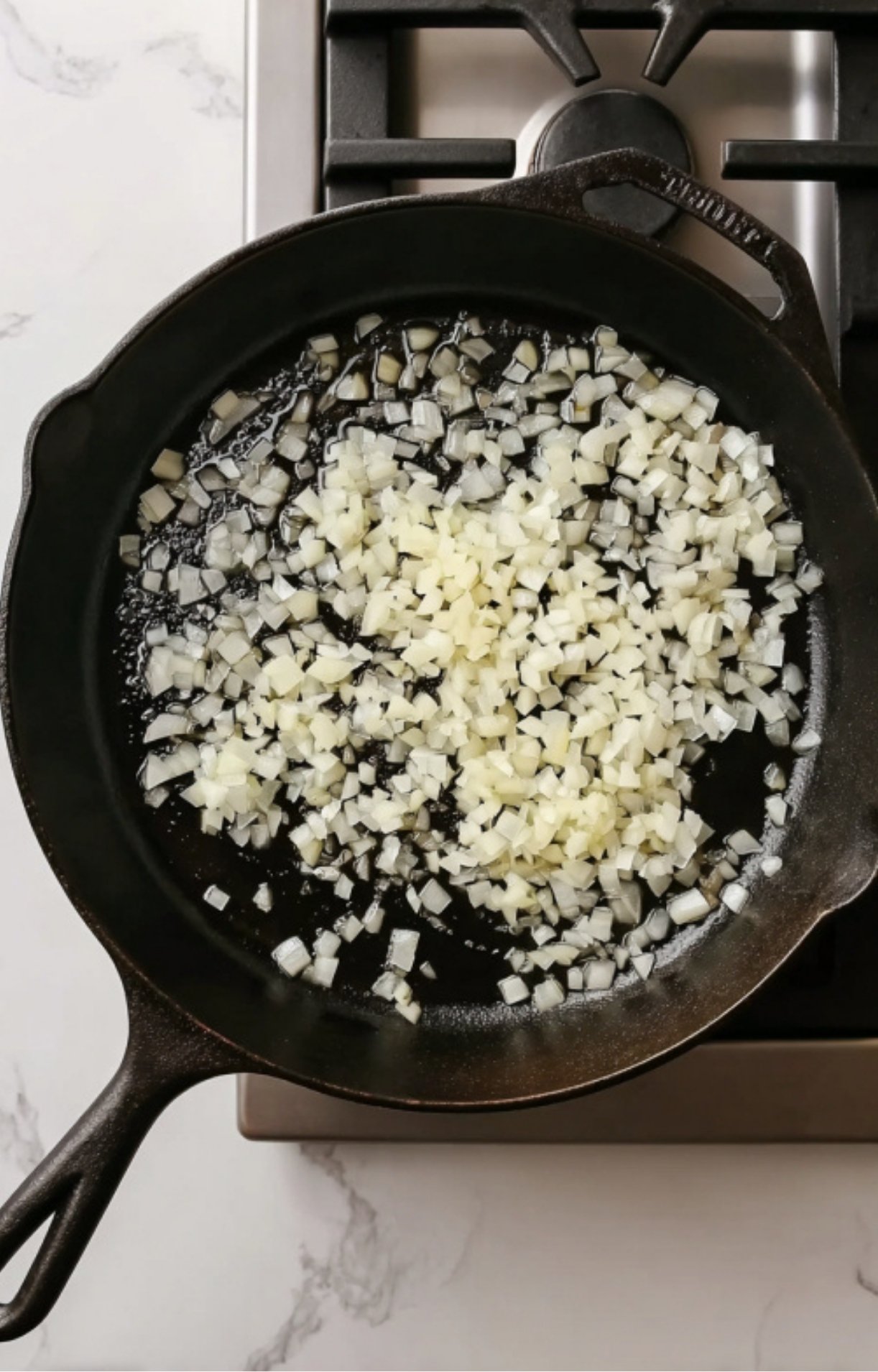 Diced onions sizzling in a cast iron skillet, the essential start for rich and flavorful veal scallopini in red sauce.
