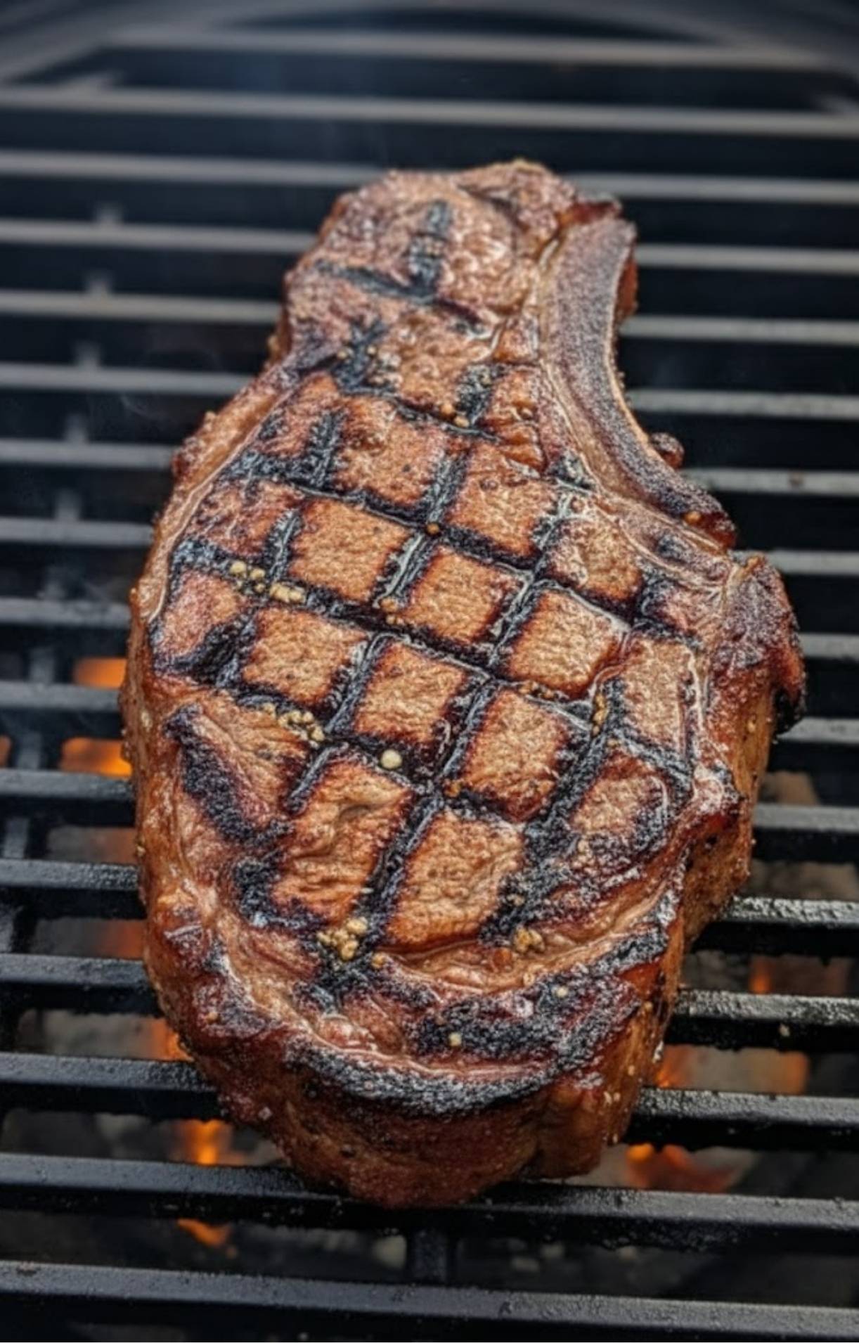 Ribeye steak sizzling on the grill with deep sear marks. Great for pairing with bold red chimichurri and outdoor grilling.
