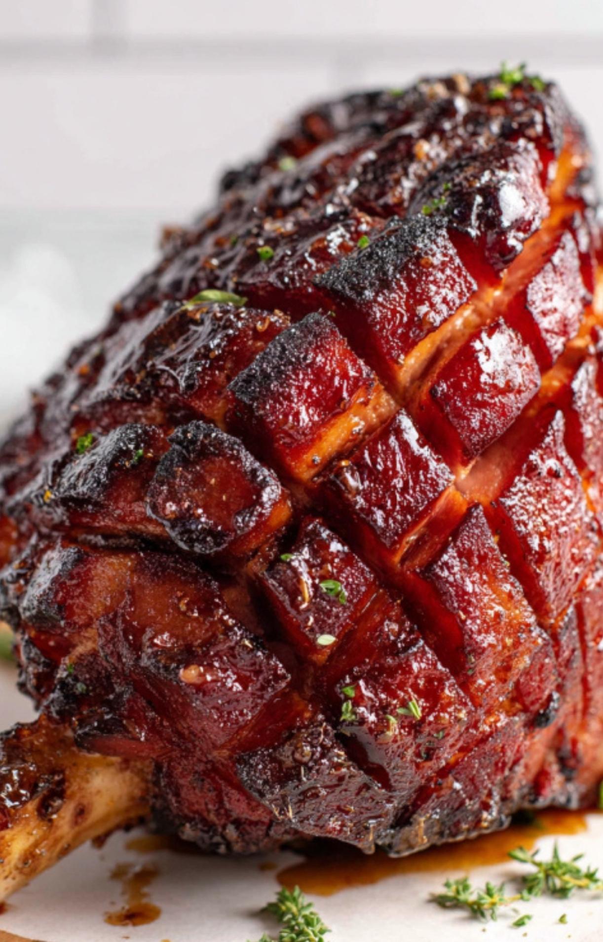 Close up of a juicy smoked ham with a dark cherry glaze and diamond-shaped scoring, ready to serve for the holidays.