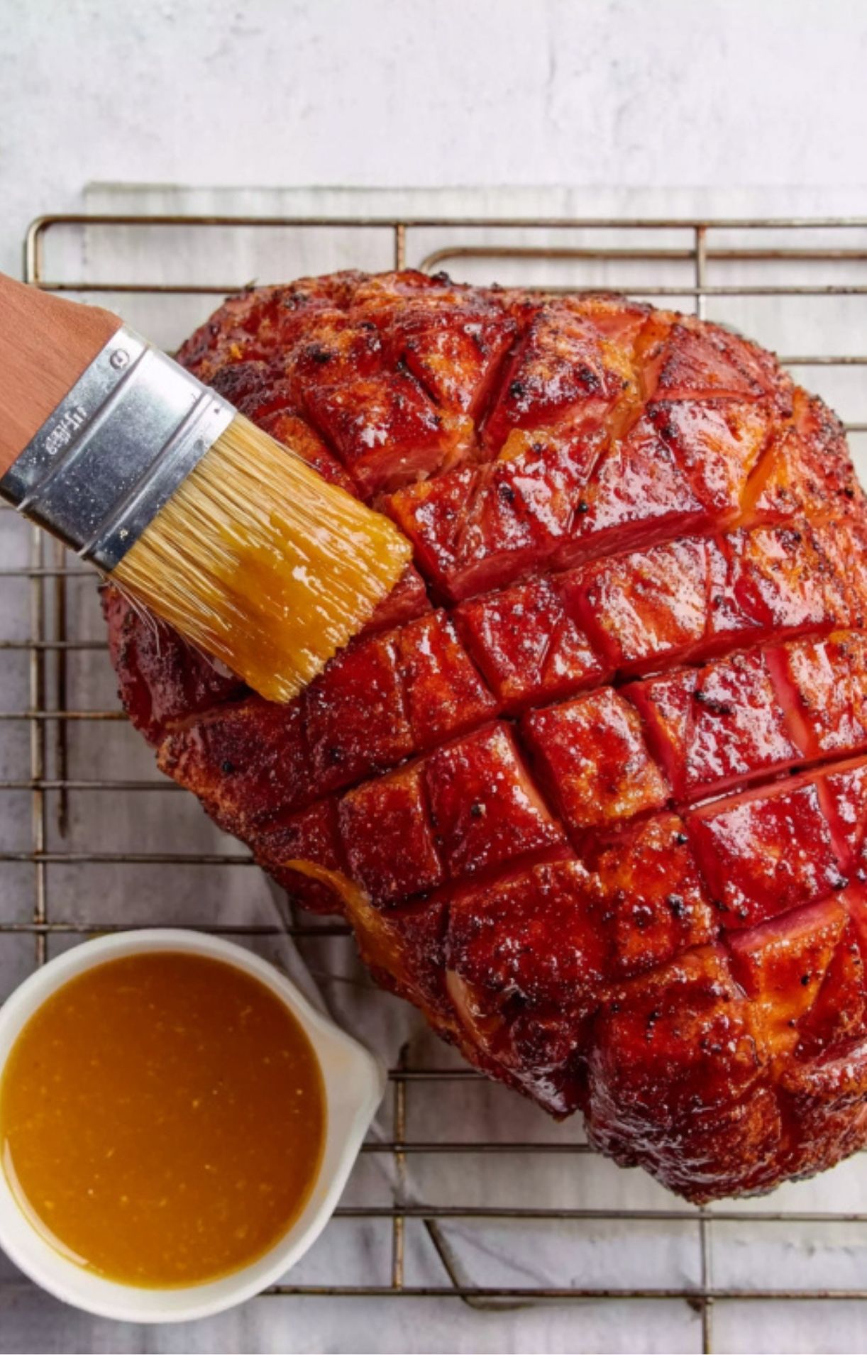 Brushing sweet glaze over smoked fresh ham on cooling rack