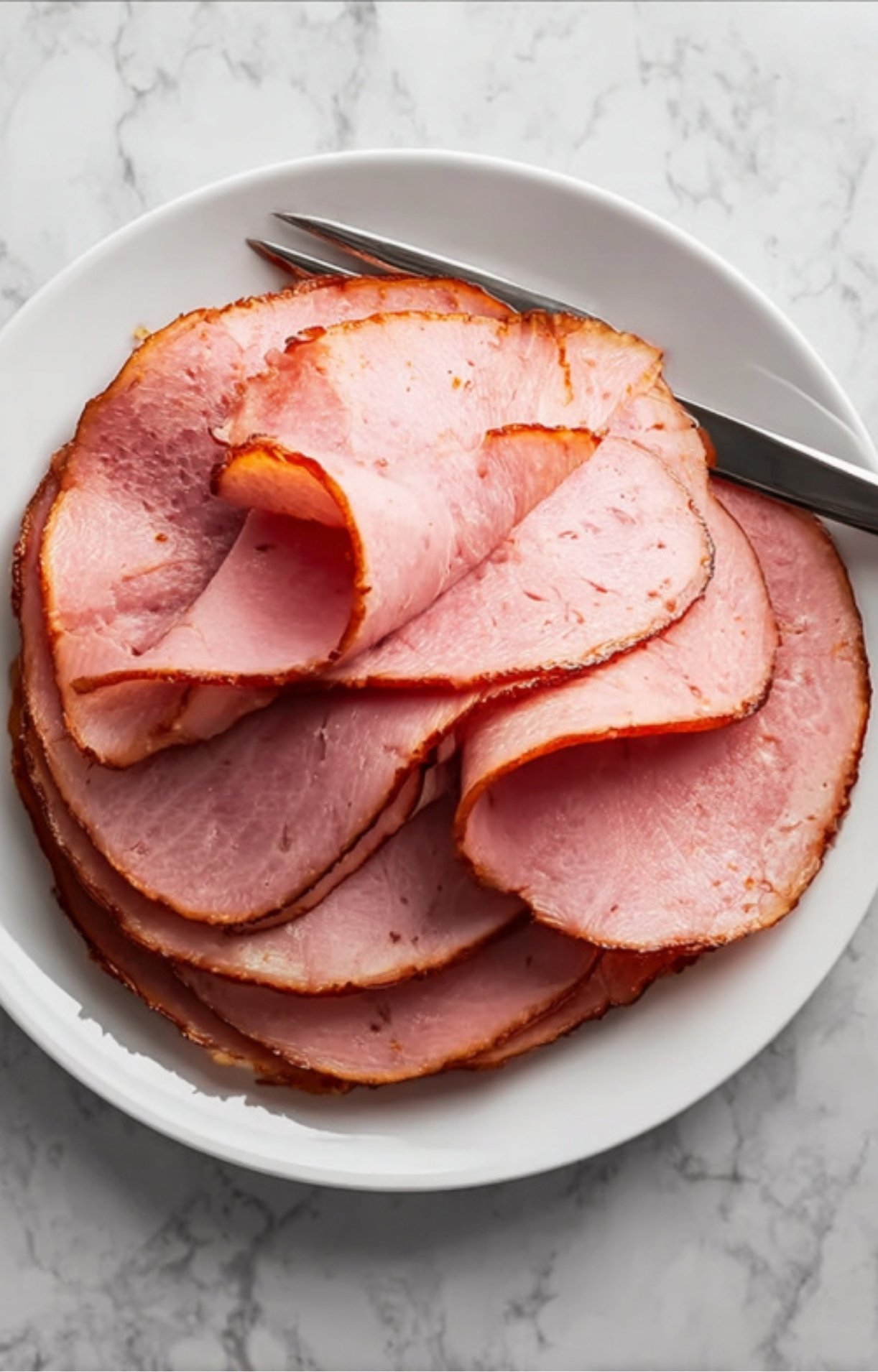 Plate of sliced smoked ham with golden edge, baked in oven, ready for holiday dinner