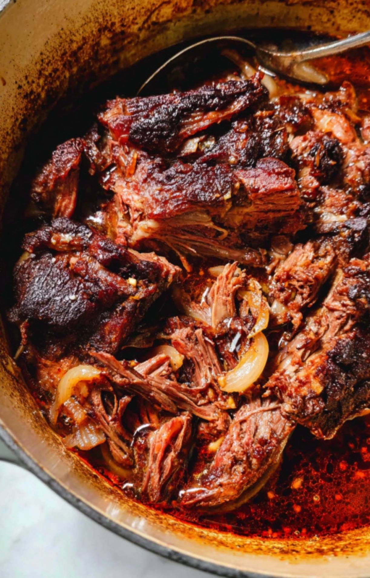 The finished roast pulling apart into succulent pieces within a concentrated, dark reduction.