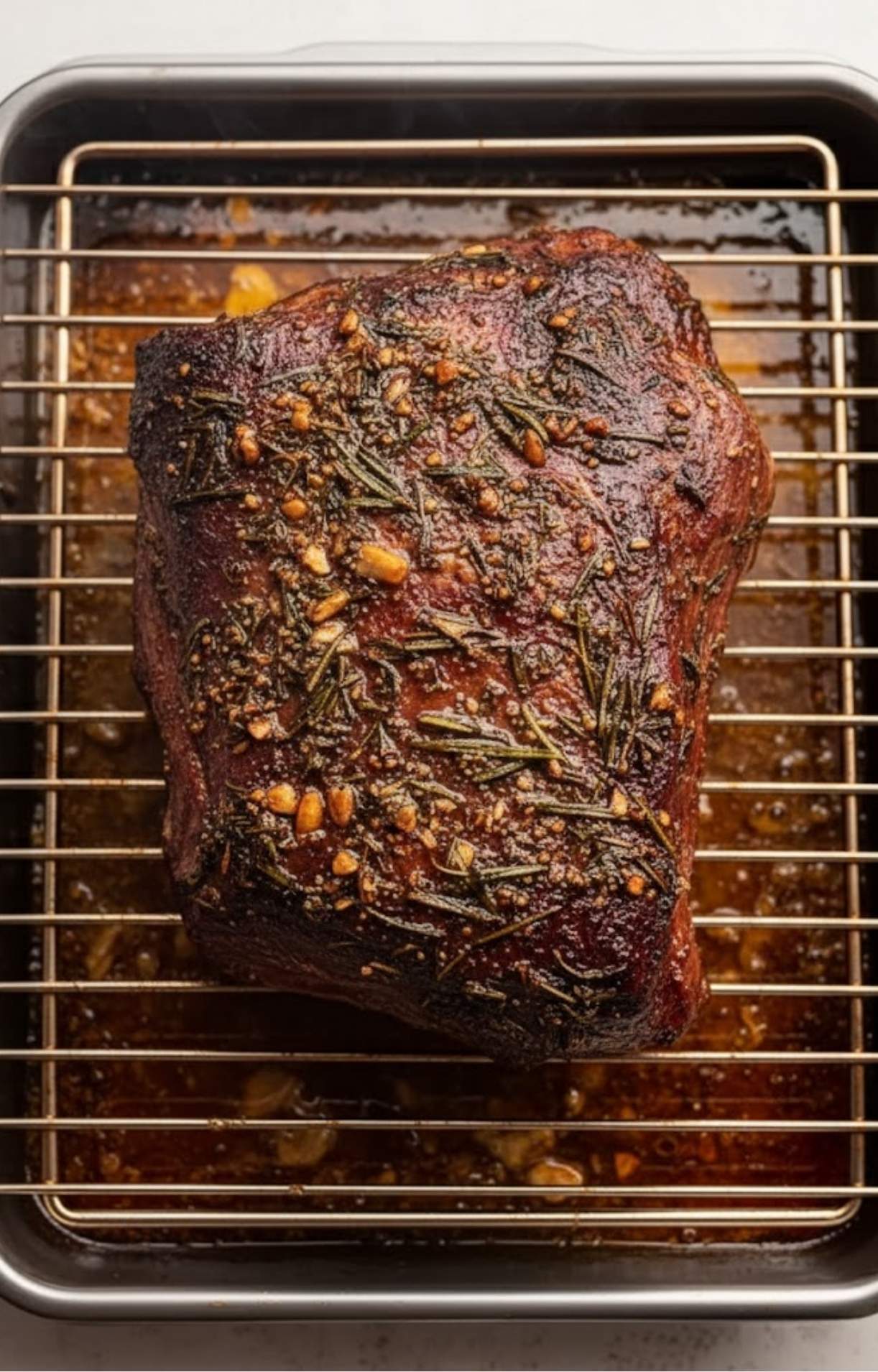 A perfectly browned and cooked Chuck Tender Roast resting on a wire rack after being roasted with fresh herbs.
