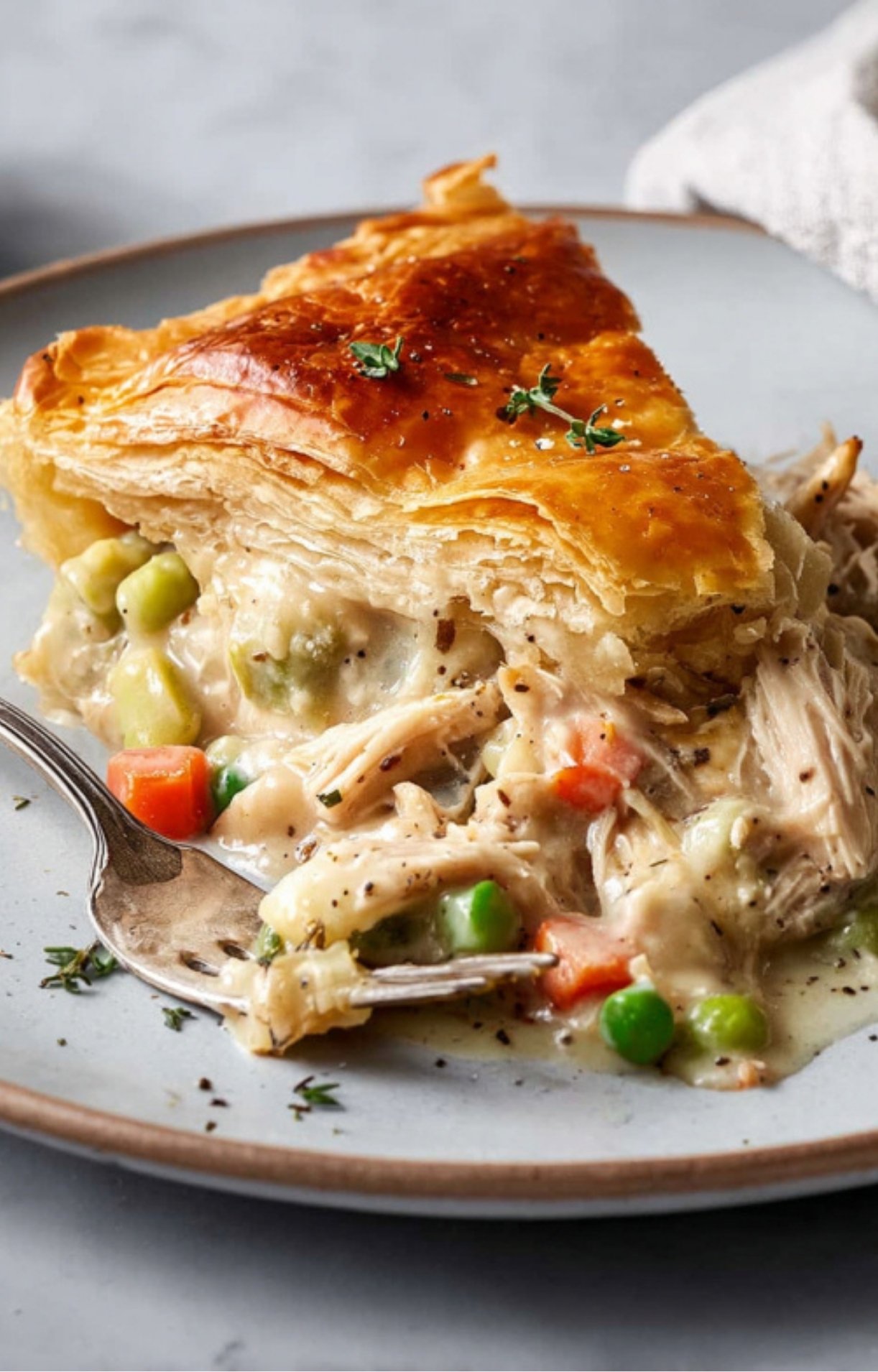 A macro shot of a fork-tender piece of Turkey Pot Pie with Puff Pastry, highlighting the many layers of the golden crust.