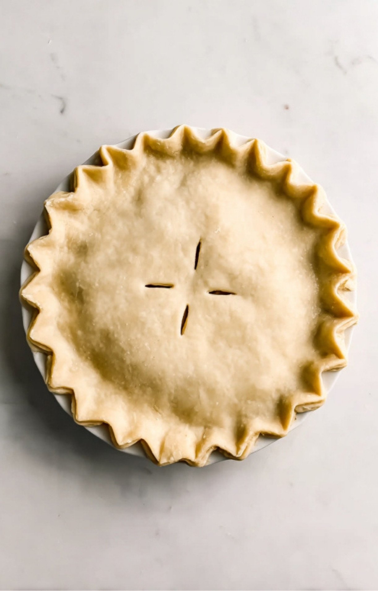 Top-down view of an unbaked Dad’s Turkey Pot Pie with a decorative crimped edge and steam vents cut into the center.
