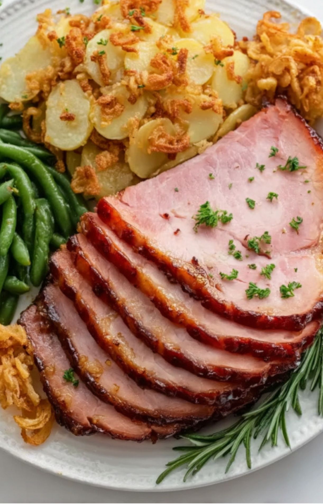 Sliced double smoked ham served with green beans and crispy potatoes, perfect holiday meal.