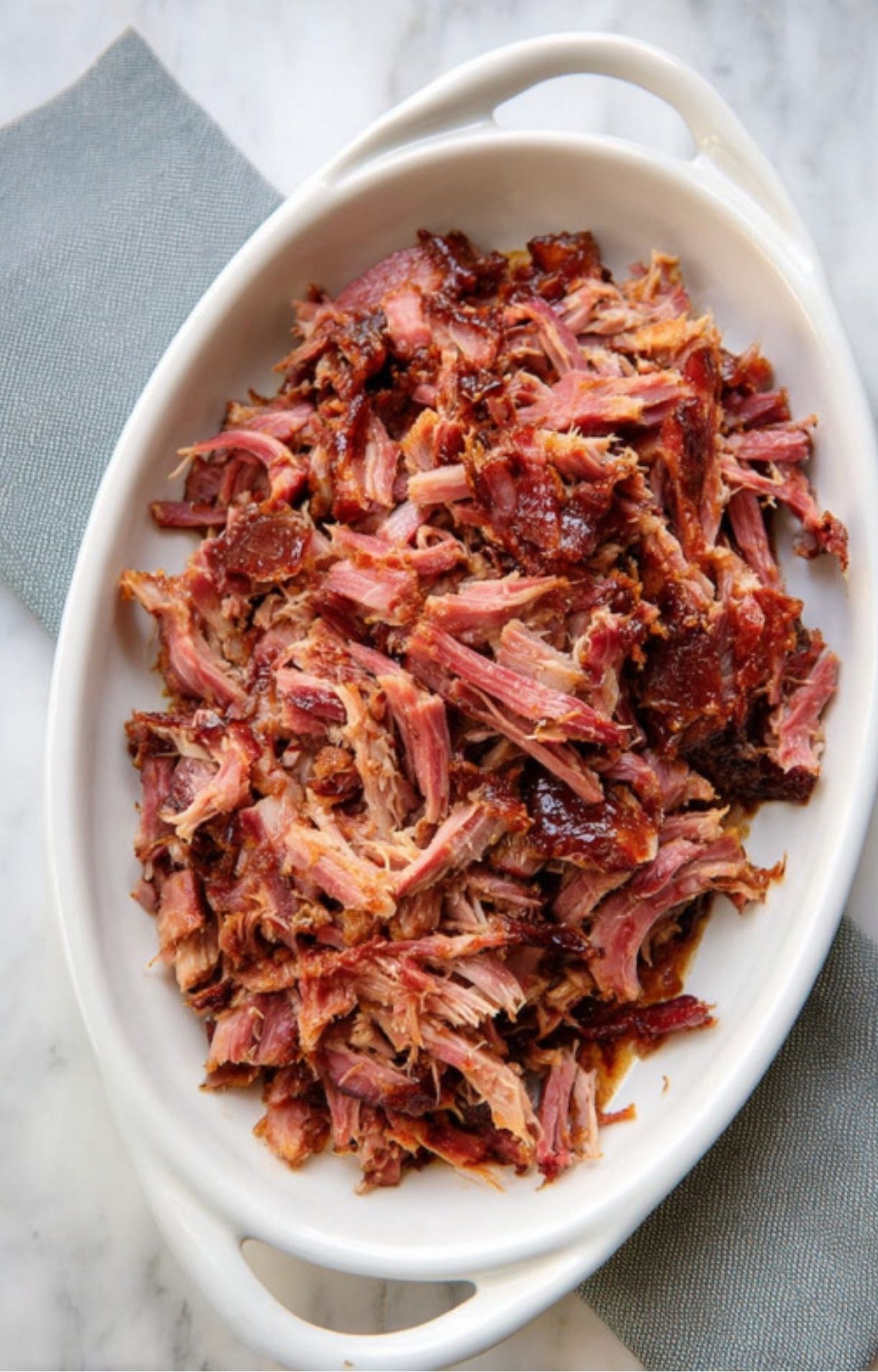 Shredded smoked ham in a white serving dish, juicy and tender