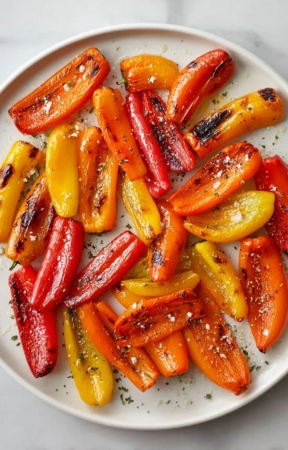 Plate filled with colorful grilled mini sweet peppers sprinkled with sea salt and pepper, ready to eat.