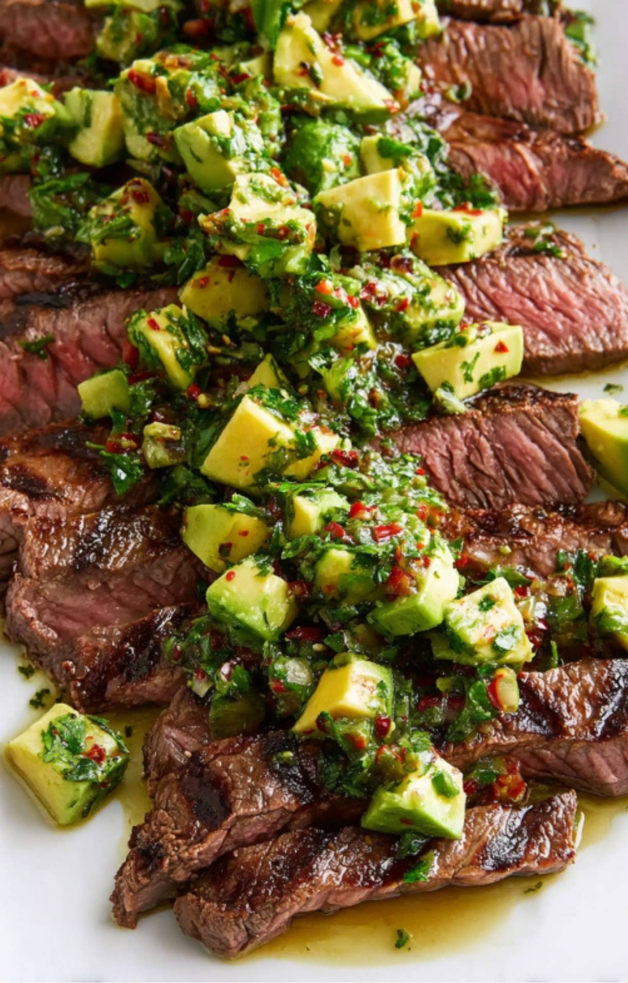 Sliced grilled flank steak topped with chunky avocado chimichurri sauce. A juicy, colorful steak recipe perfect for summer grilling and high protein dinners.