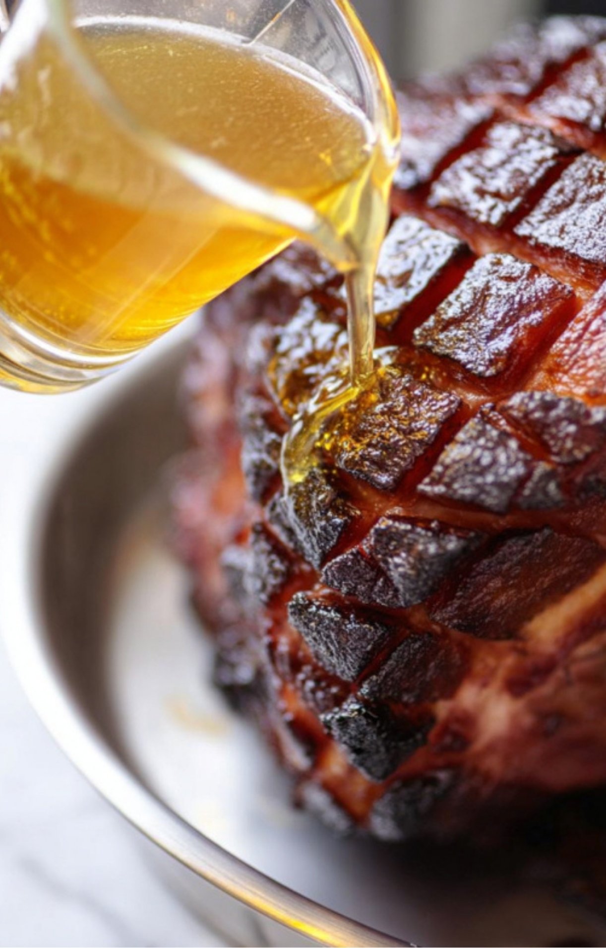 Pouring sweet citrus glaze over smoked ham for a holiday dinner