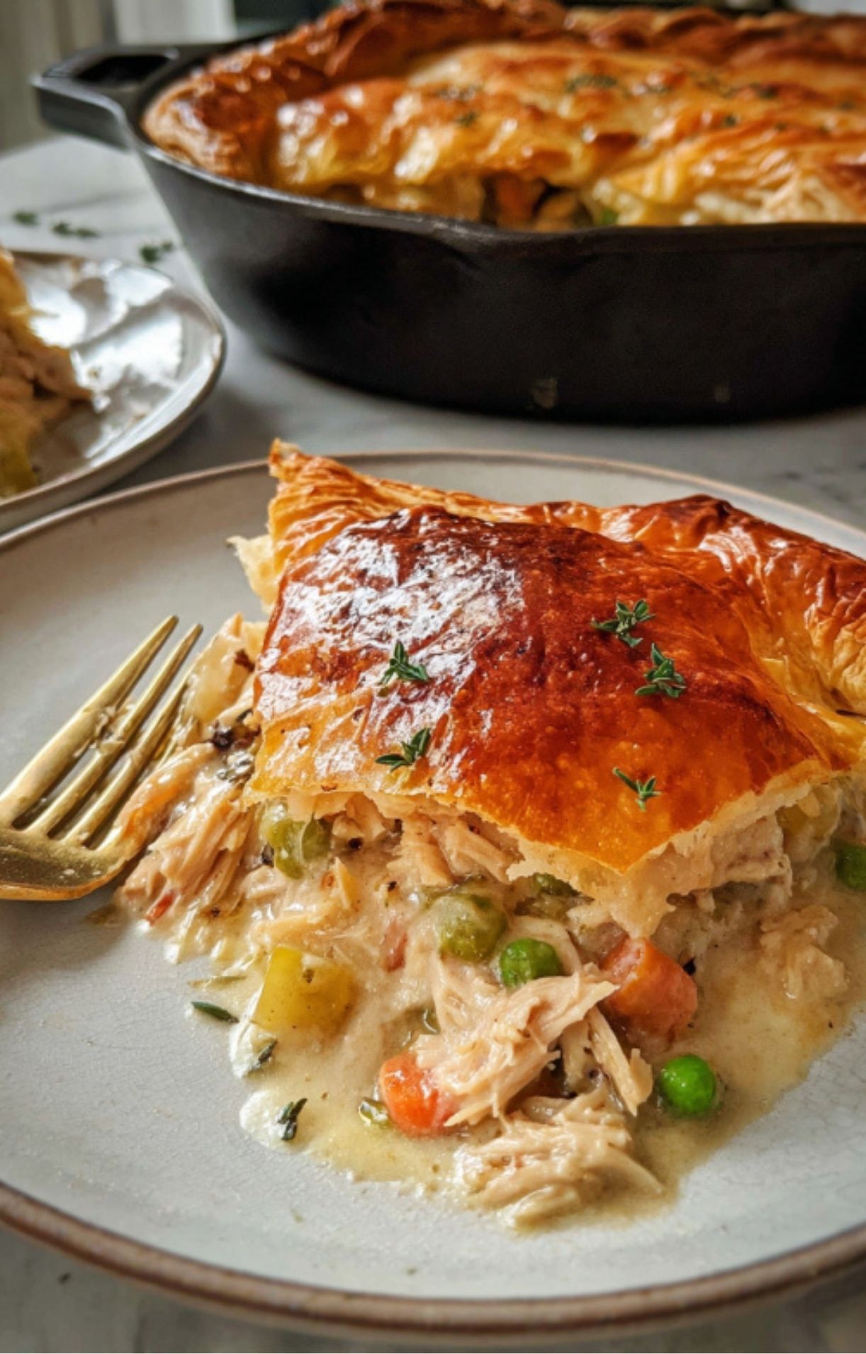 A generous slice of Turkey Pot Pie with Puff Pastry on a plate, showing the layers of flaky crust and creamy turkey filling.