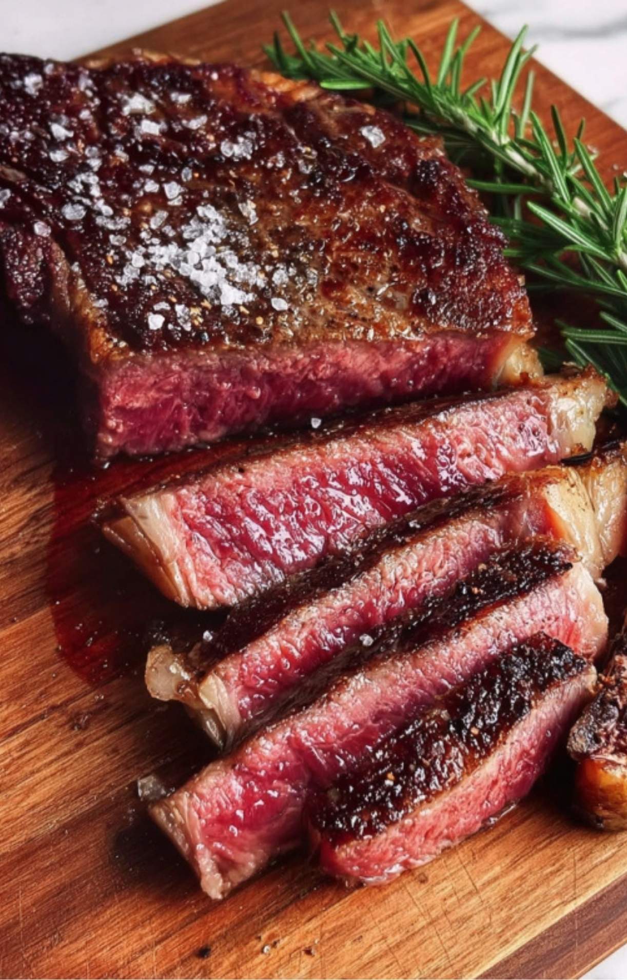 A perfectly seared, sliced medium-rare rib eye steak served on a white plate with roasted asparagus, carrots, and cherry tomatoes, highlighting rib eye steak nutrition and a balanced meal.