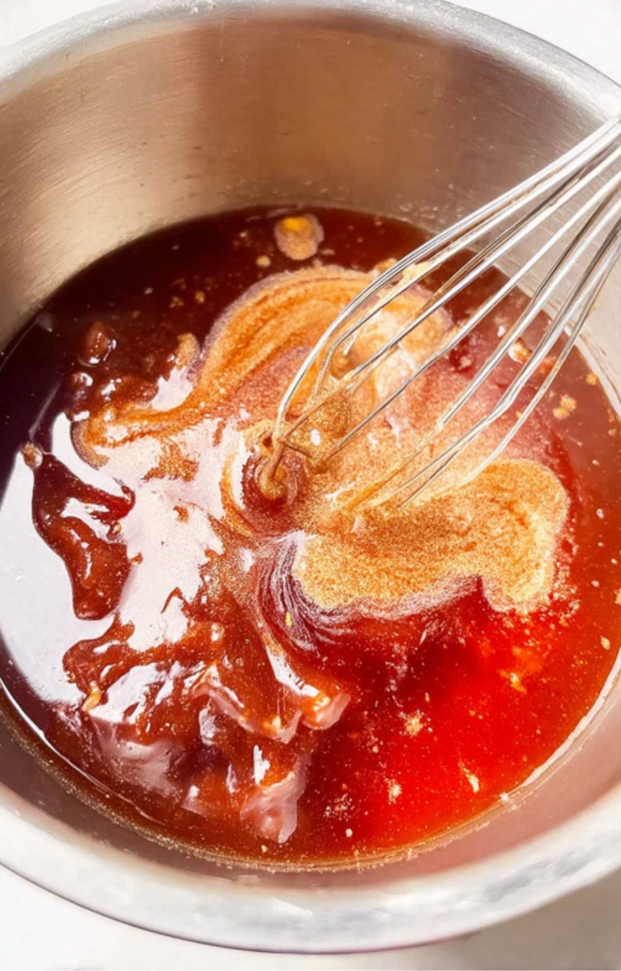 Maple brown sugar glaze being whisked in a saucepan, for coating double smoked ham.