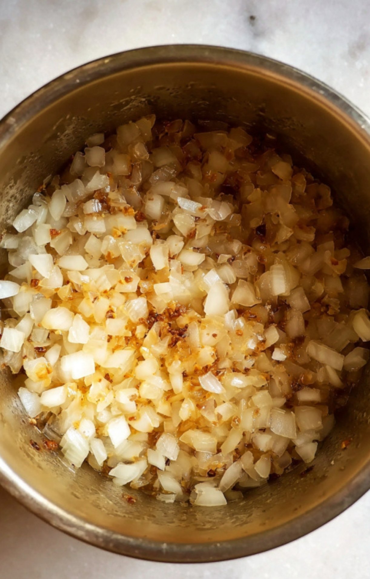 Diced white onions cooking in a pot until softened and slightly golden for the taco base.
