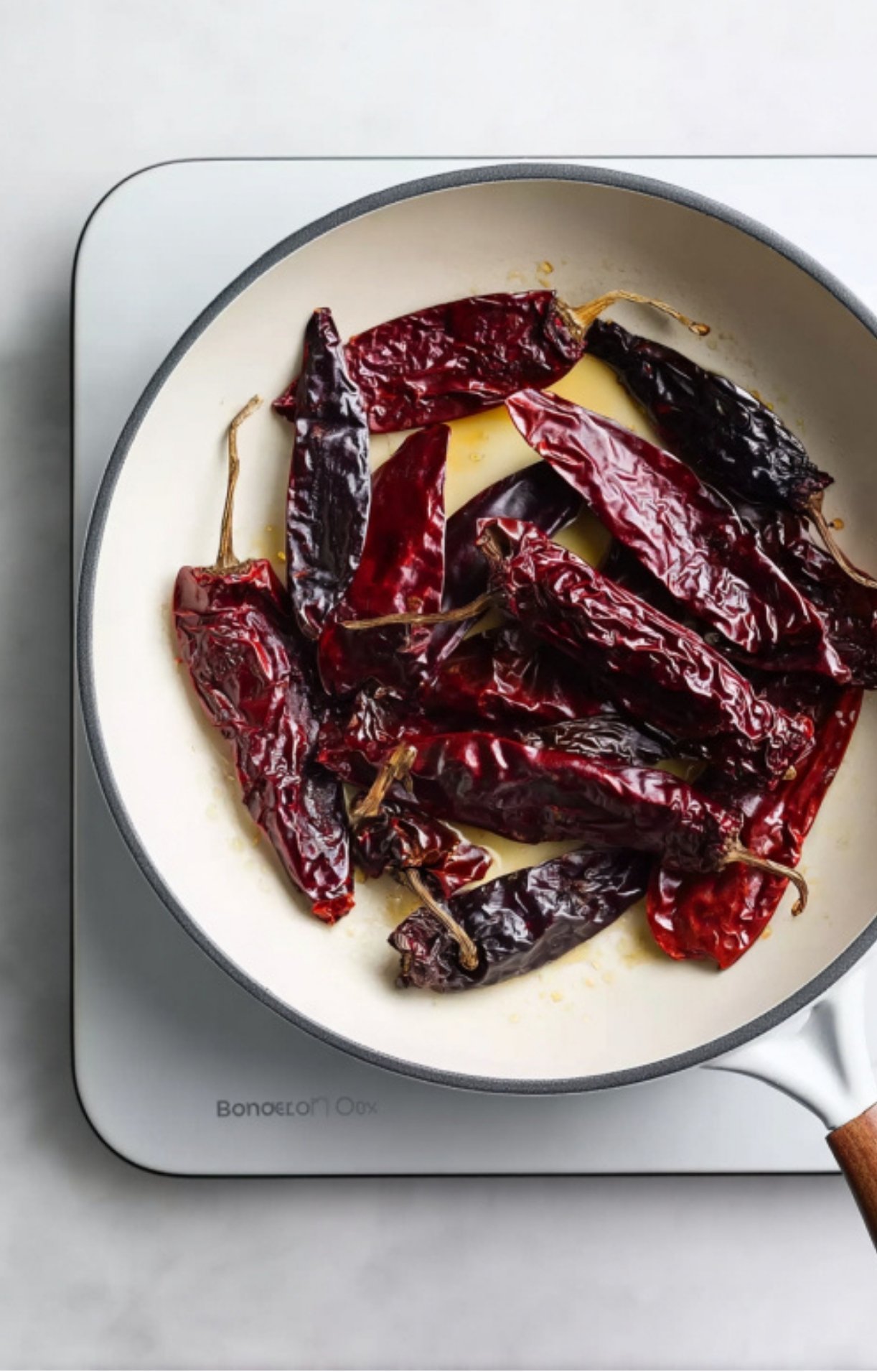 Whole dried red chilies, such as Guajillo or Ancho, being lightly toasted in a pan to release their oils.