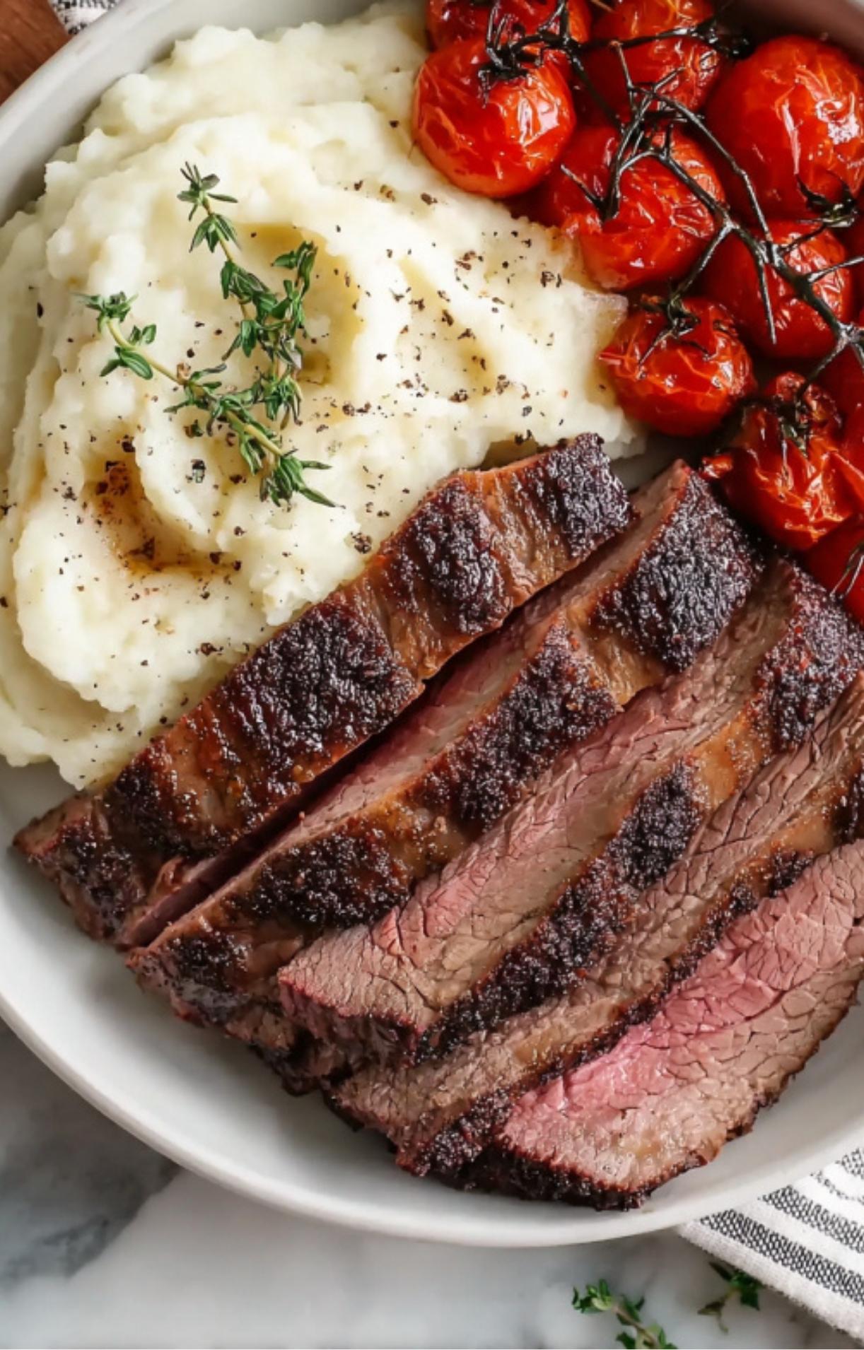 An overhead view of sliced chuck roast, creamy mashed potatoes, and vine-ripened tomatoes.