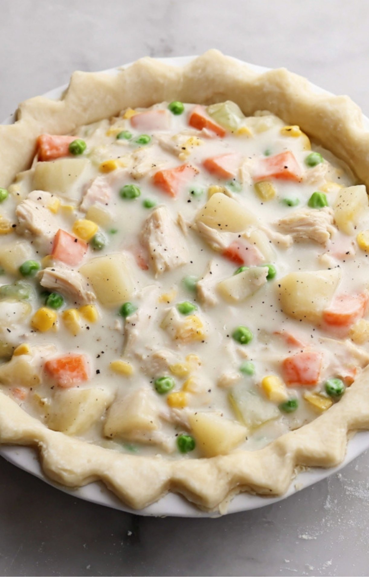 Creamy white gravy poured over the turkey and vegetable mixture inside a fluted pie crust.