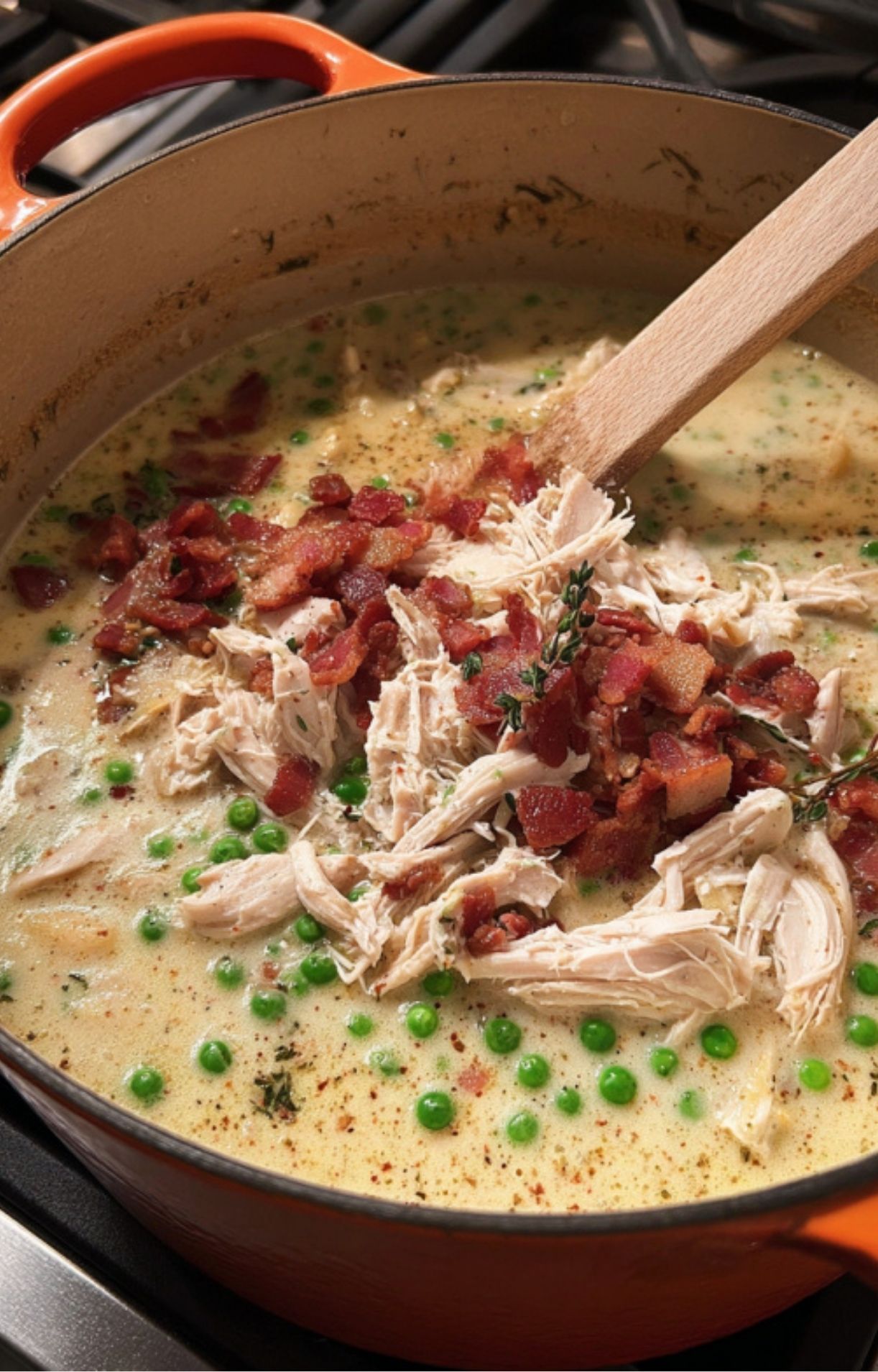 Shredded turkey and crispy chopped bacon being stirred into a large orange Dutch oven filled with a creamy vegetable soup base.