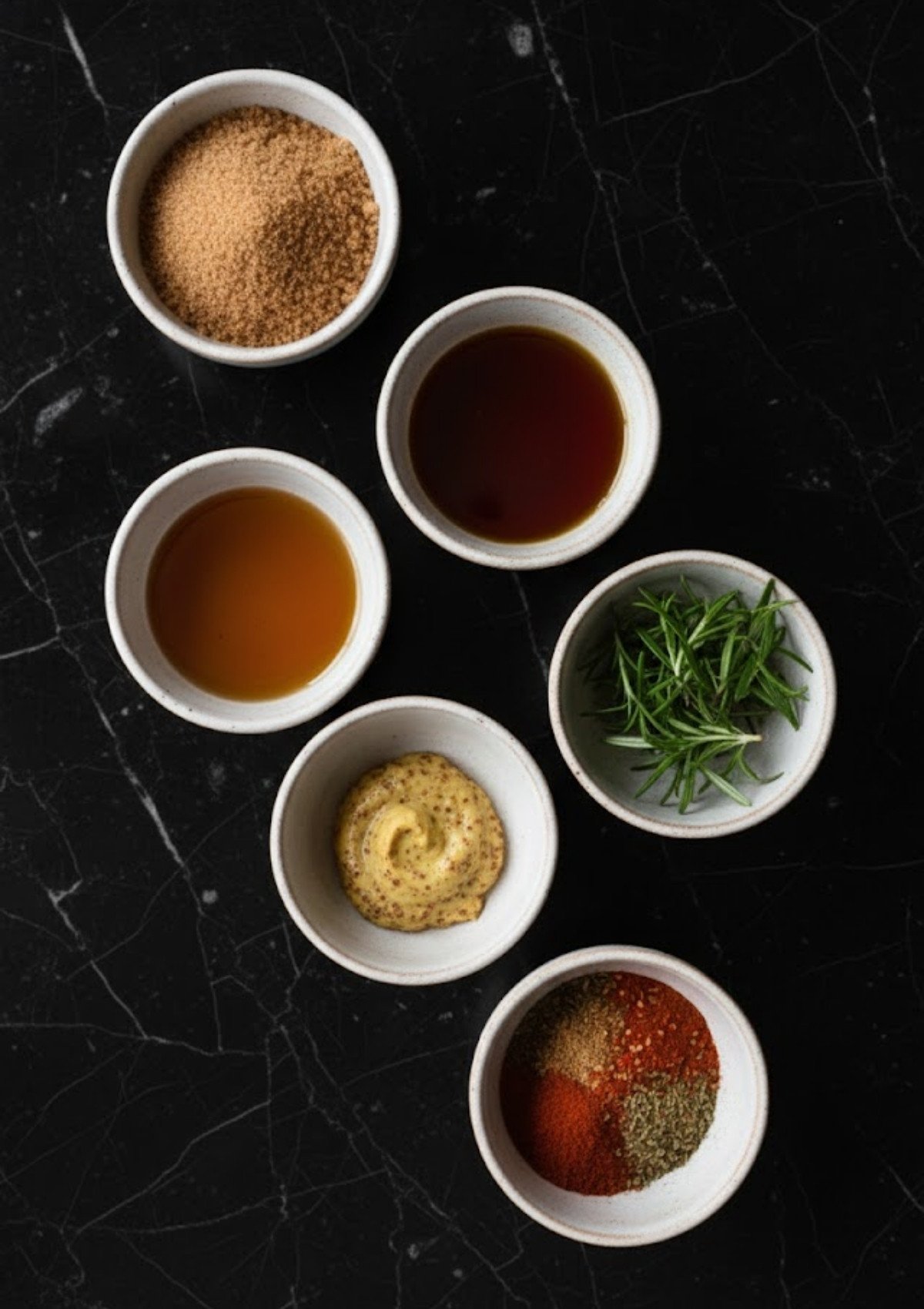 Bowls of brown sugar, maple syrup, mustard, spices, and rosemary for homemade smoked ham glaze