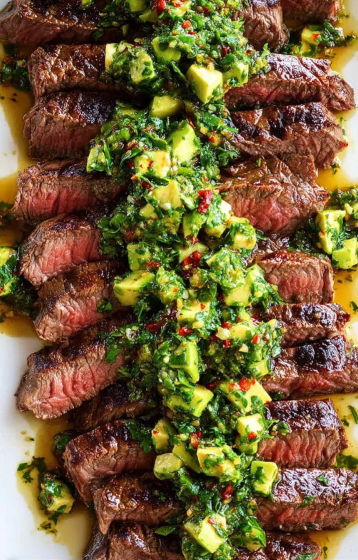 Sliced steak arranged on a platter with bright avocado chimichurri drizzled on top. Perfect for BBQs, weeknight meals, and gluten free eating.