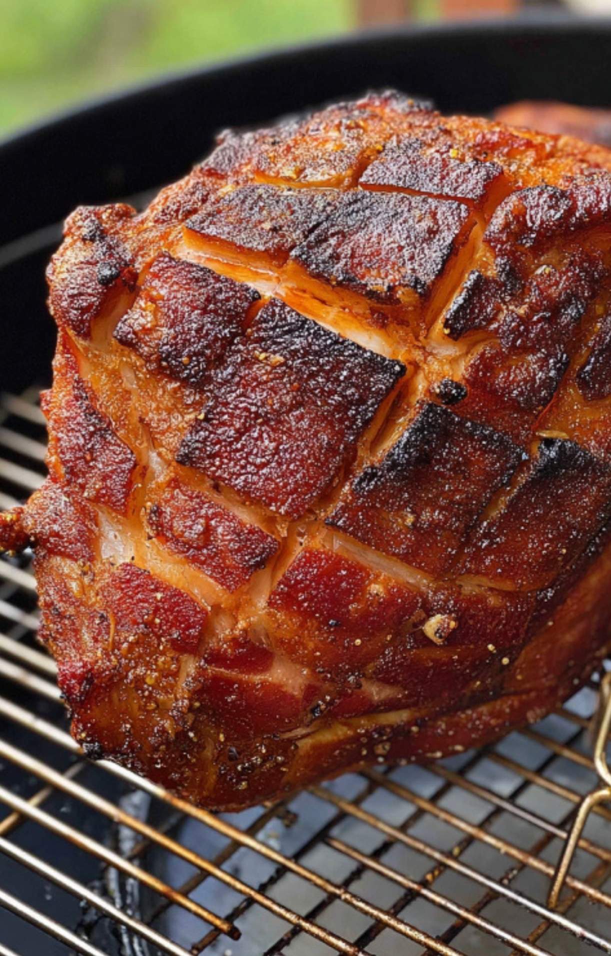 Whole ham with scored skin slowly smoking on a grill rack, developing a dark, flavorful crust.