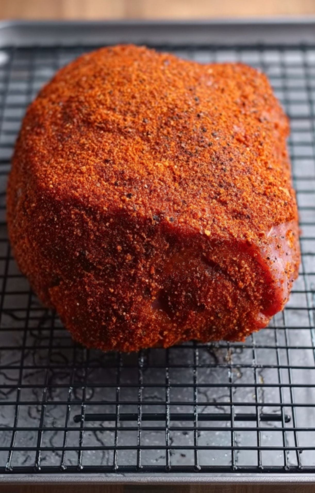 Fresh ham with dry rub seasoning on wire rack