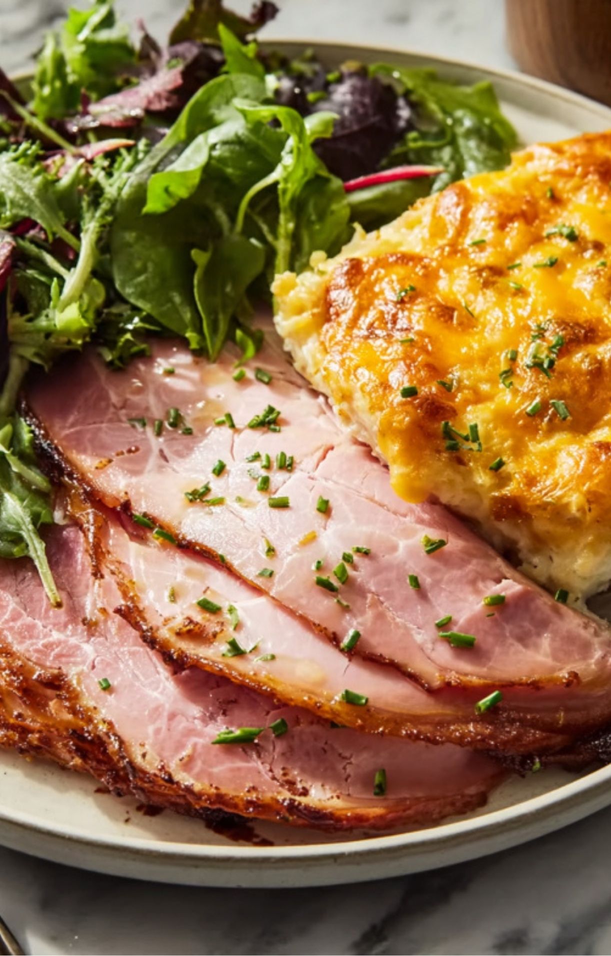 Sliced smoked ham served with scalloped potatoes and salad, ideal internal temperature
