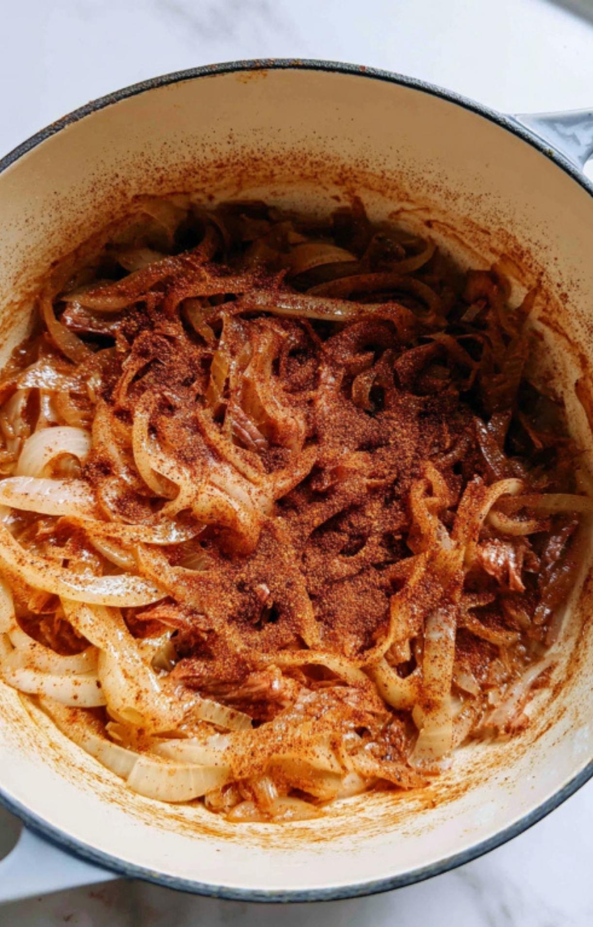 Golden sautéed onions in the pot coated with a generous layer of red and brown spices.