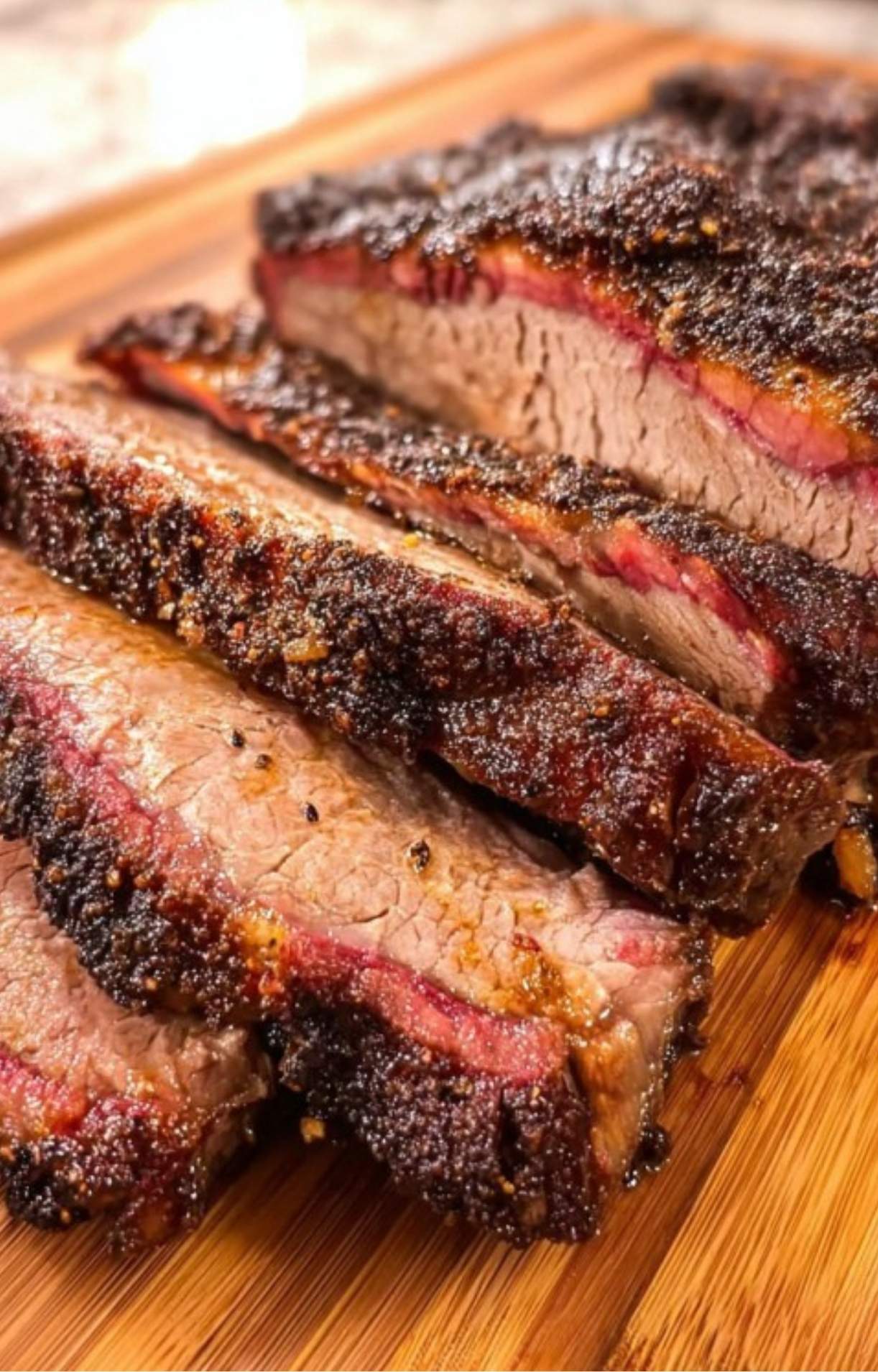 Detailed view of moist, tender chuck roast slices resting on a wooden board with a prominent smoke ring.