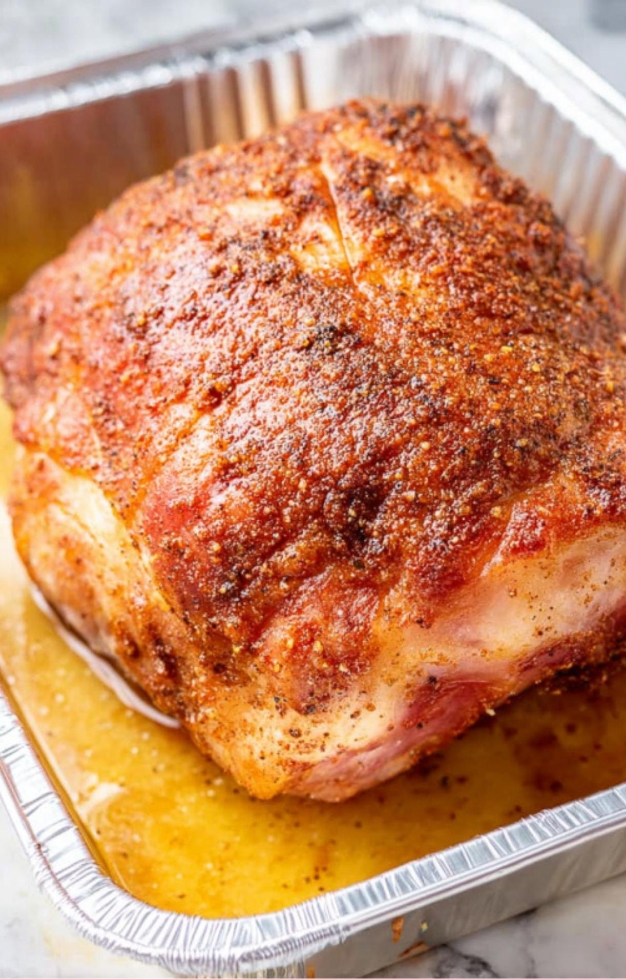 Double smoked ham in a pan, golden brown and caramelized, perfect for holiday feasts.